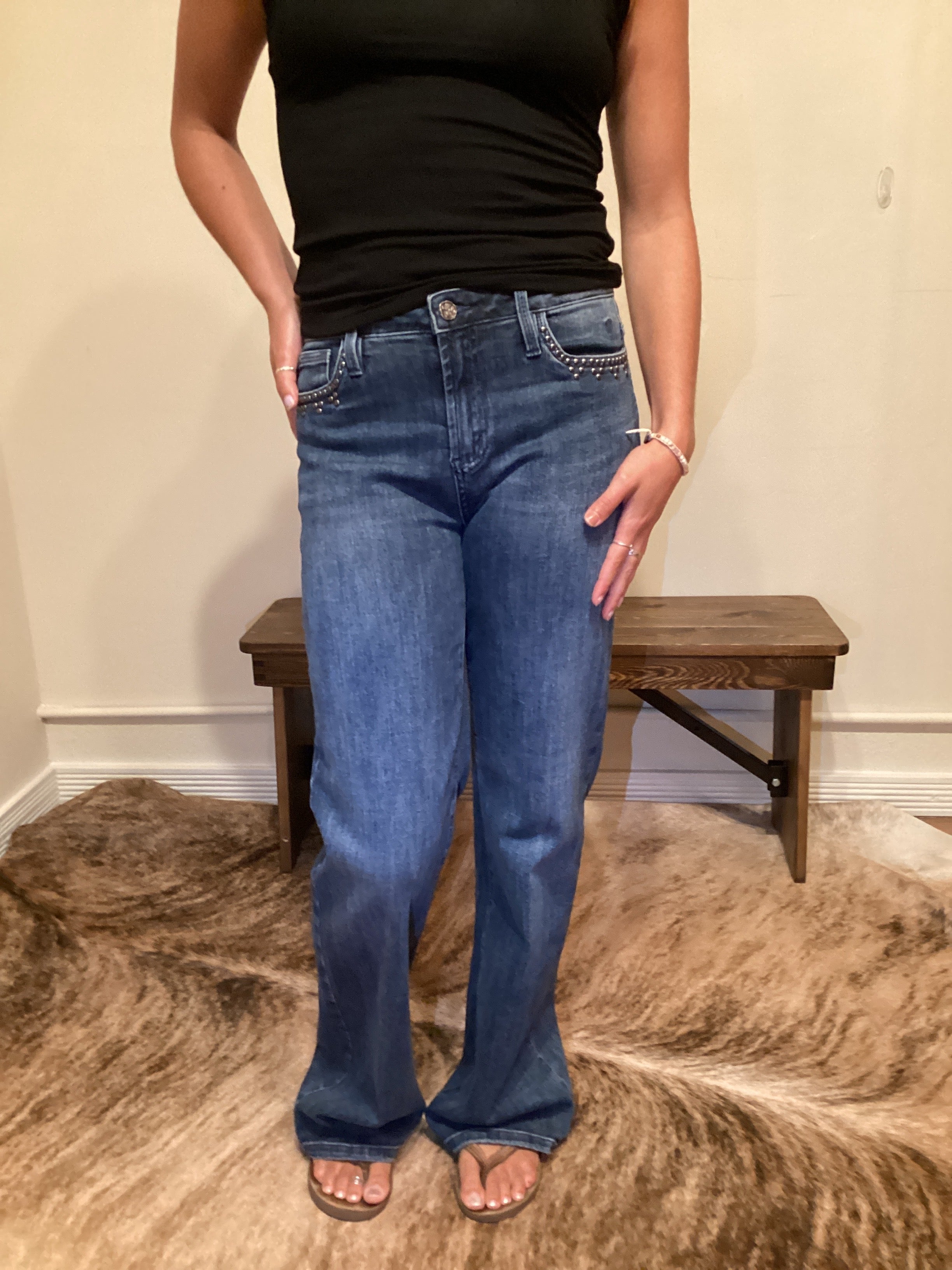 Person wearing blue jeans with stud detailing on the edge of the front pockets