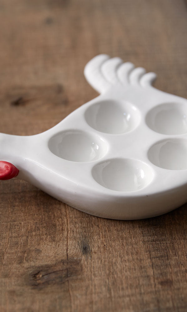 White ceramic egg holder shaped like a chicken on a wooden surface