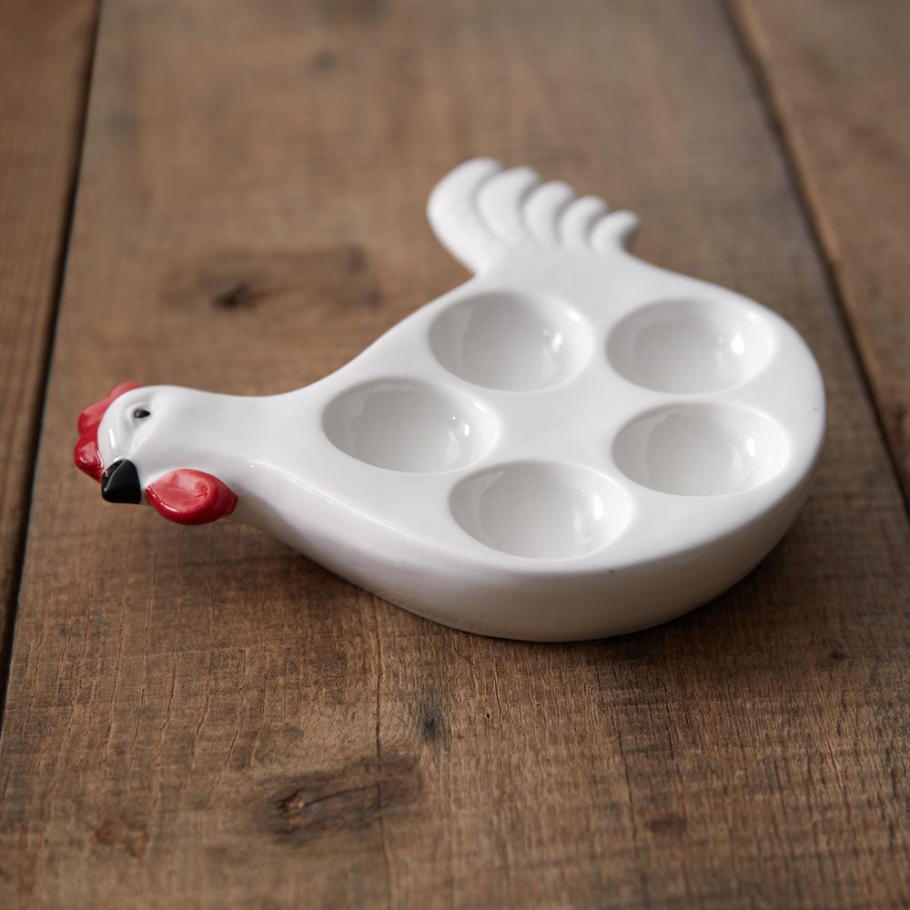 White ceramic egg holder shaped like a chicken on a wooden surface