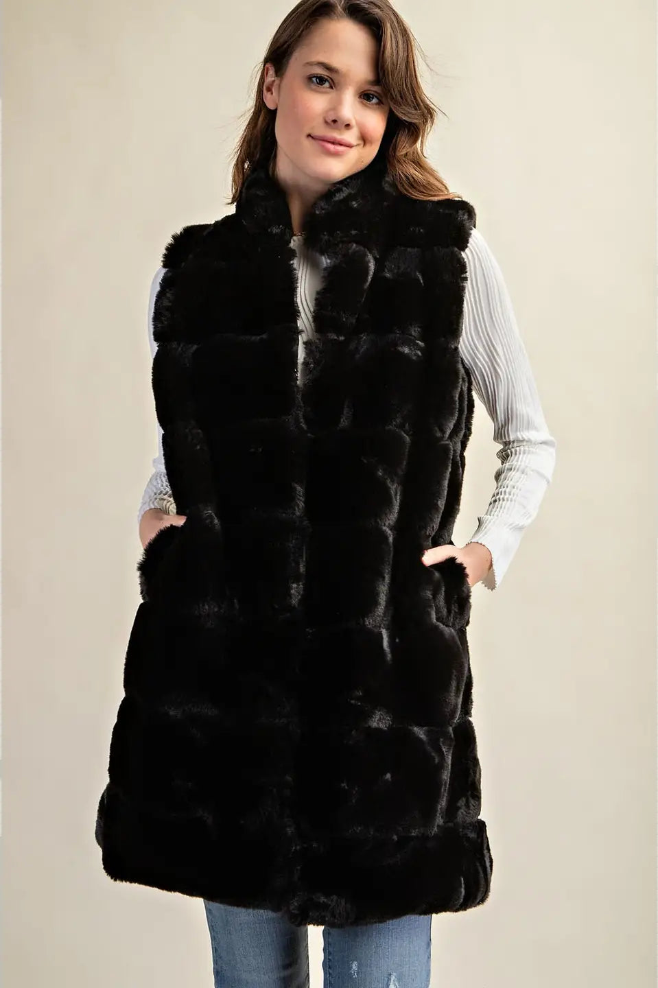 Woman wearing a black fur vest on a beige background