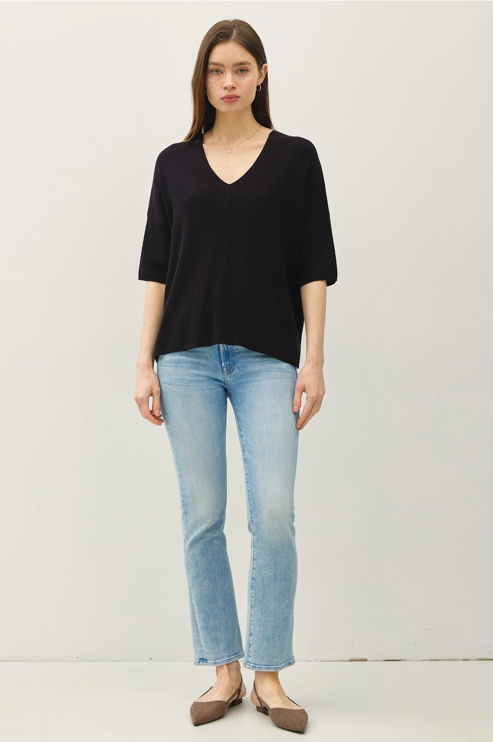 Woman wearing a black top and light blue jeans on a white background