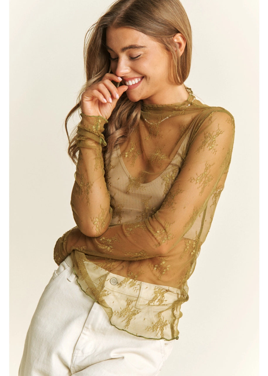 Woman wearing a sheer olive top with lace details on a plain background