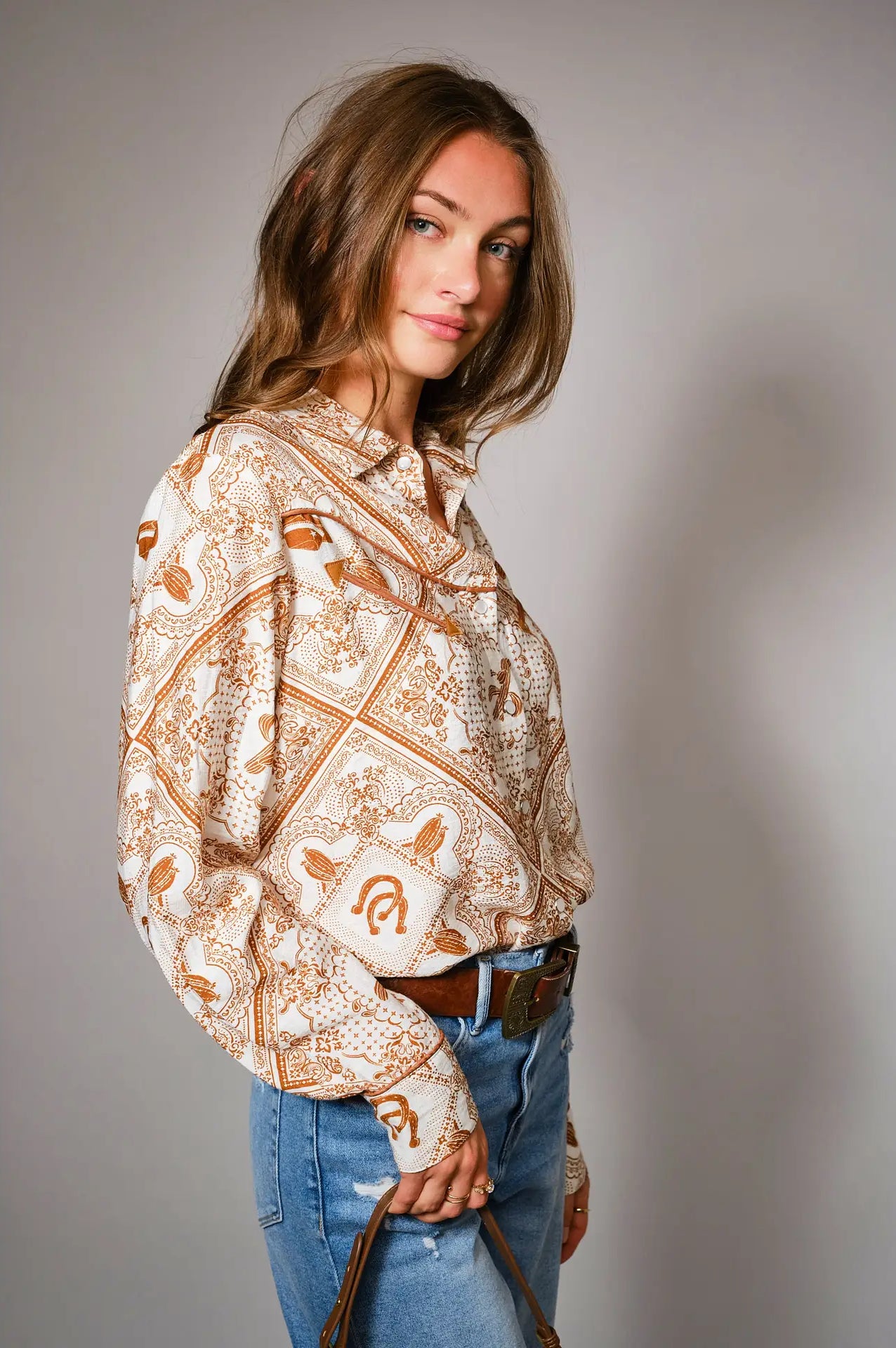 Woman wearing a western patterned blouse western color details snap shirt and jeans