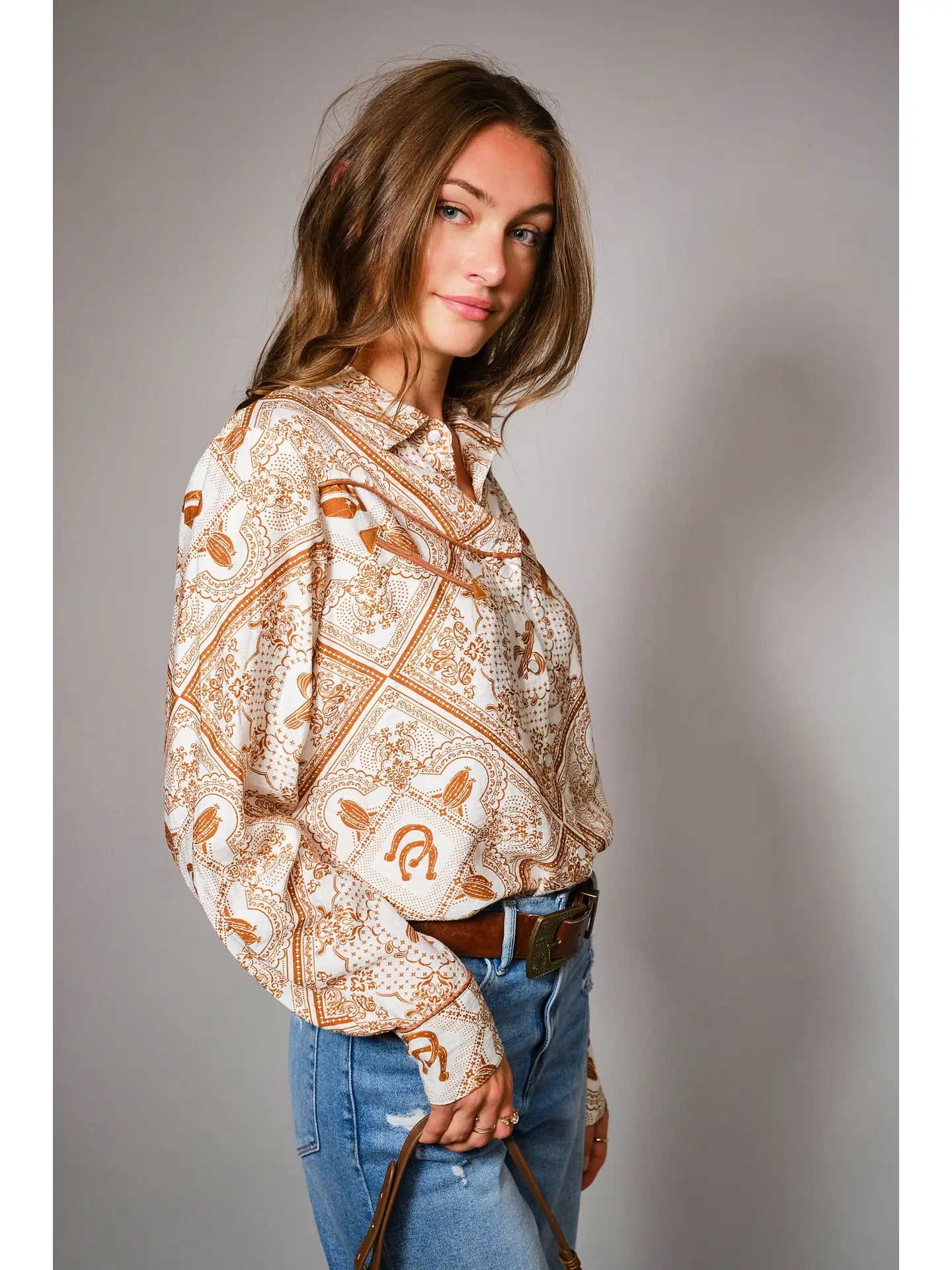 Woman wearing a western patterned blouse western color details snap shirt and jeans