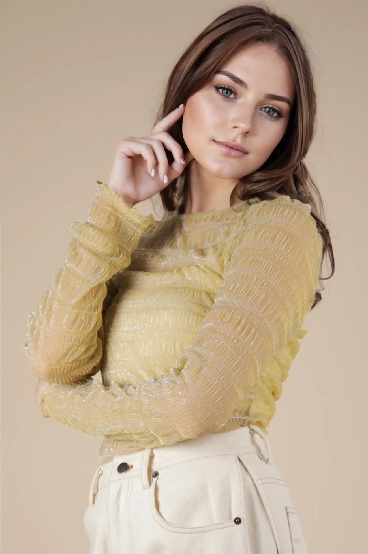 Front view: Model wearing champagne sheer lurex long-sleeve fitted top with crew/mock neck; subtle sparkle visible.