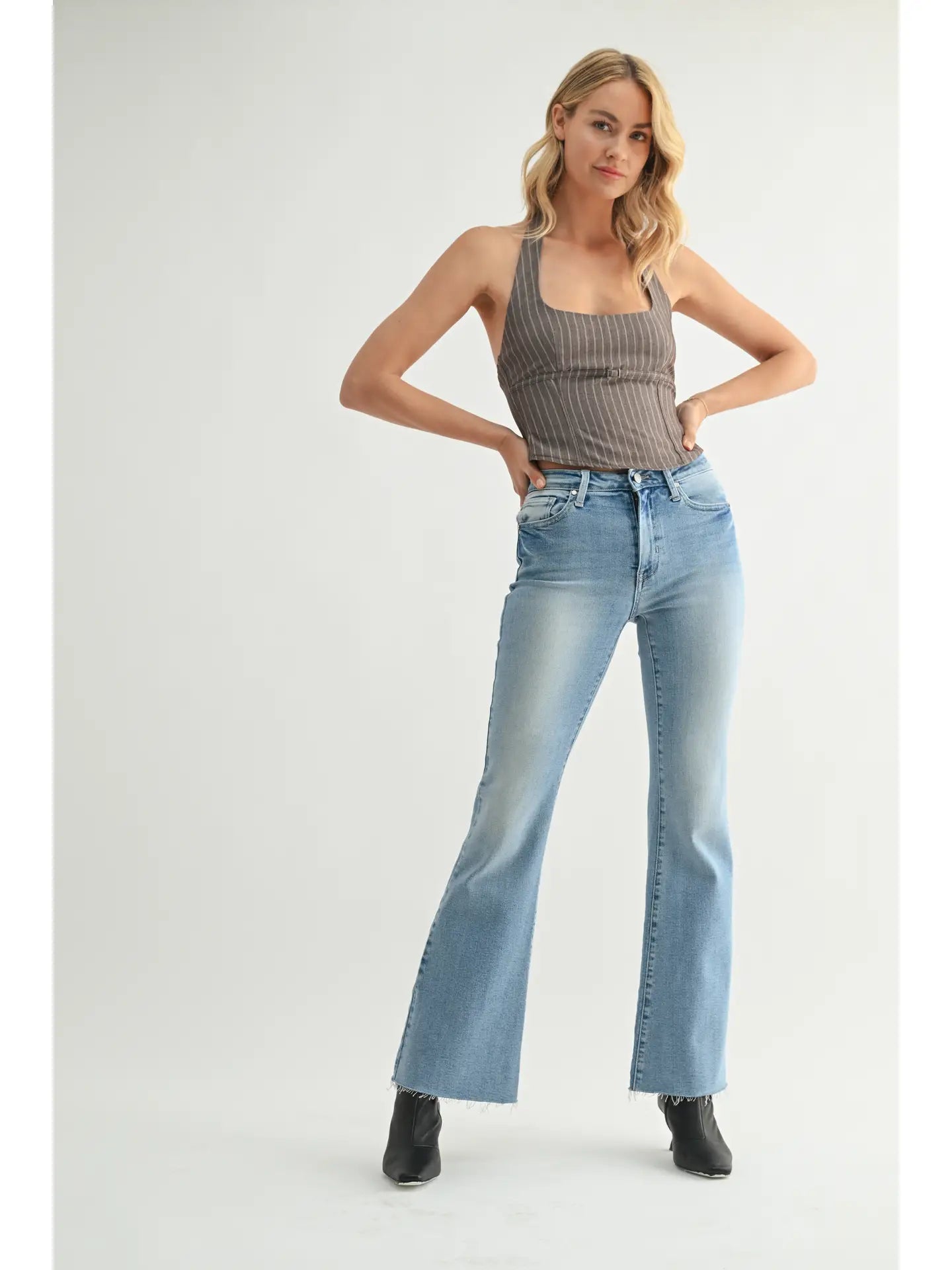 Woman wearing a ribbed tank top and light blue jeans on a white background