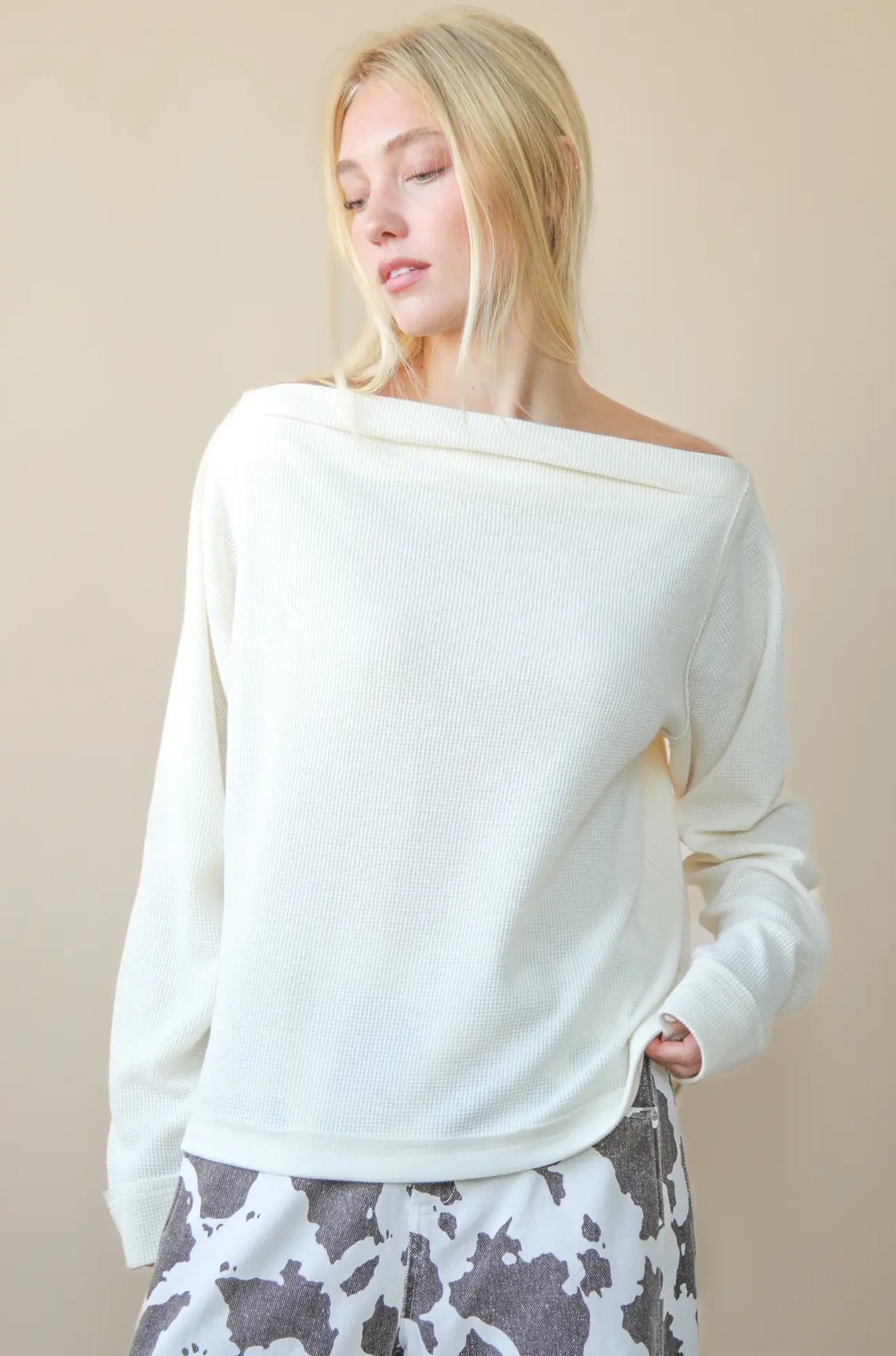 Front view of solid boat-neck cotton knit top worn slightly off-shoulder, long sleeves