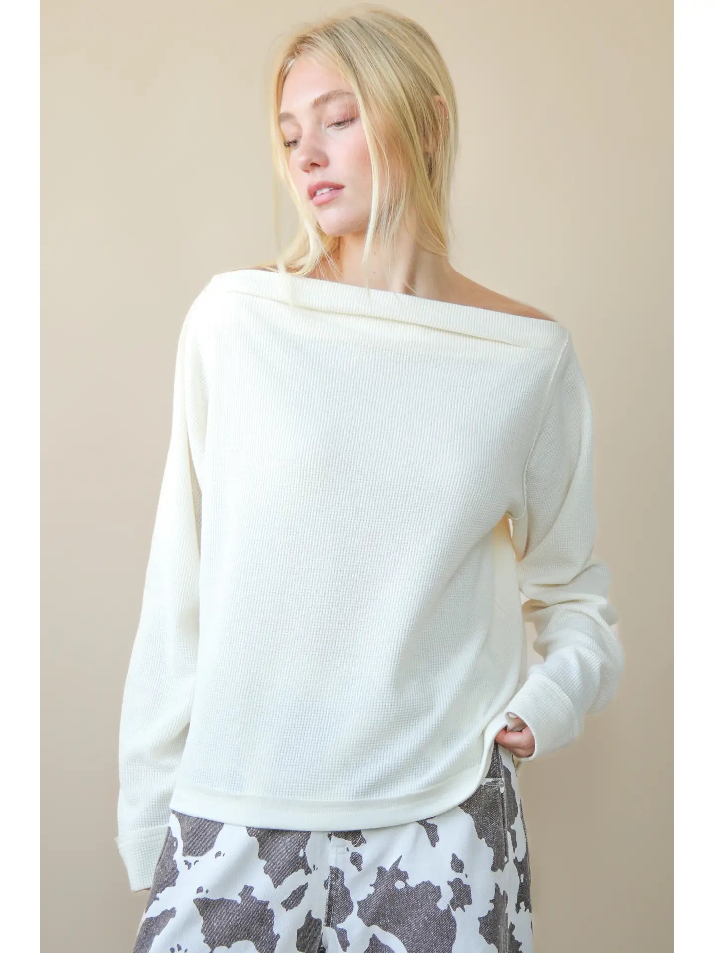 Front view of solid boat-neck cotton knit top worn slightly off-shoulder, long sleeves
