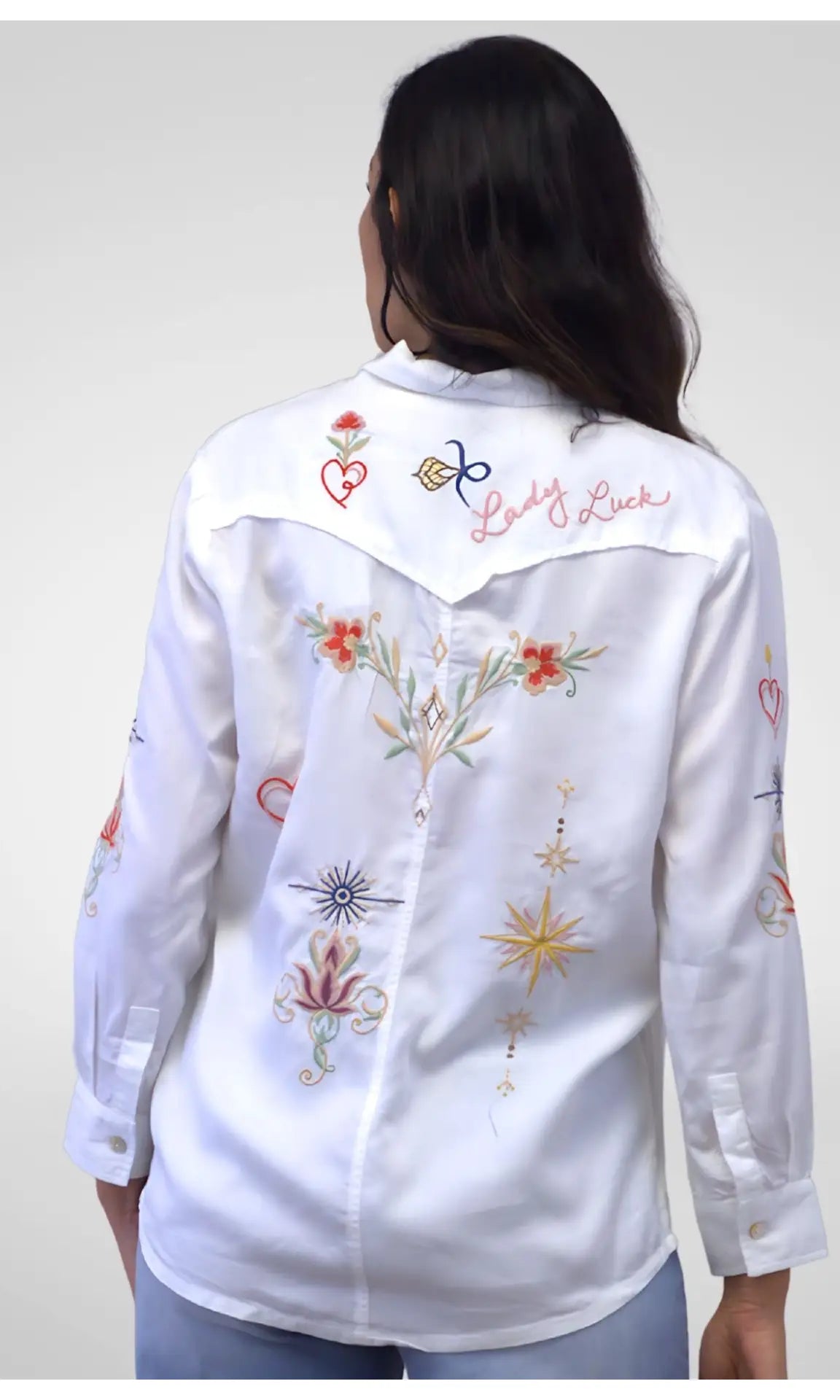 White embroidered shirt worn by a person on a plain background