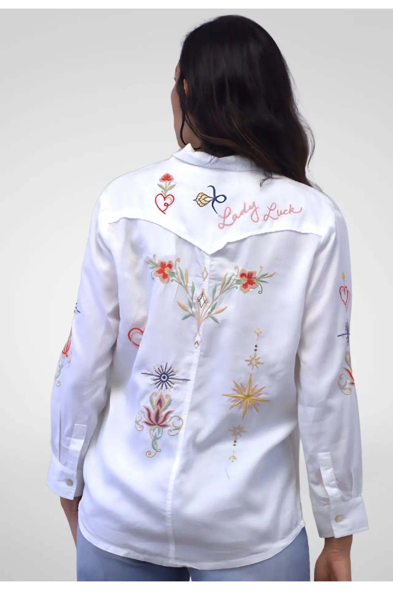 White embroidered shirt worn by a person on a plain background