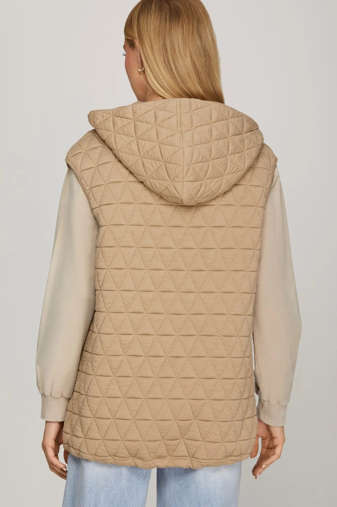 Back View Woman wearing a beige quilted vest zip up oversized fit with zipper pockets