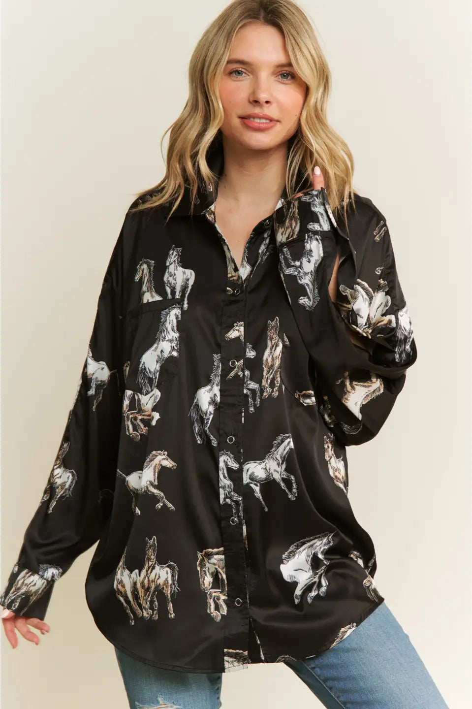 Woman wearing a black button-up shirt with horse print against a beige background