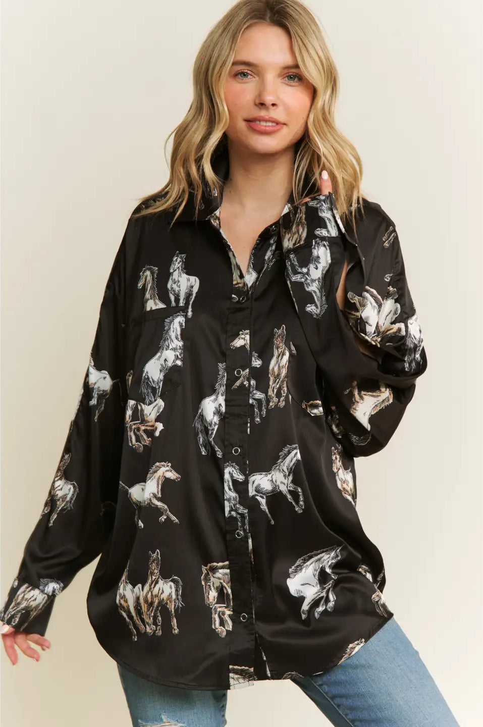 Woman wearing a black button-up shirt with horse print against a beige background