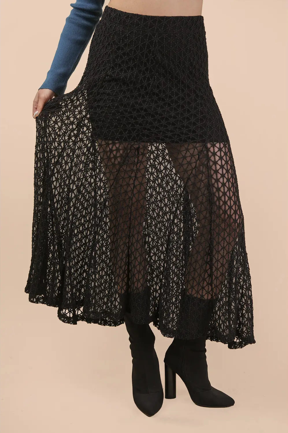 Black lace skirt worn by a person on a beige background
