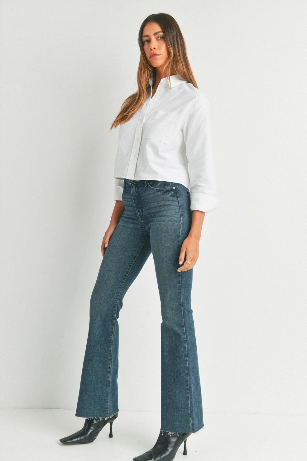 Woman wearing a white shirt and blue jeans on a white background