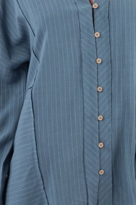 Close-up of dusty-blue striped shirt placket and chevron pinstripe detail with wooden buttons.