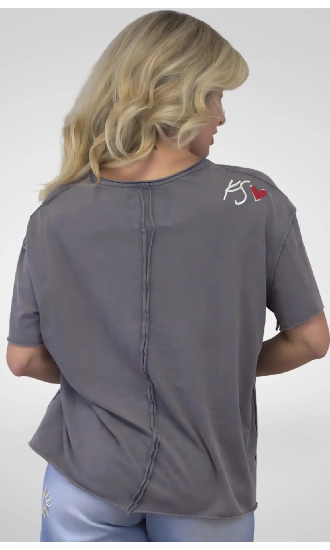 Person wearing a gray shirt with a logo on the back against a white background