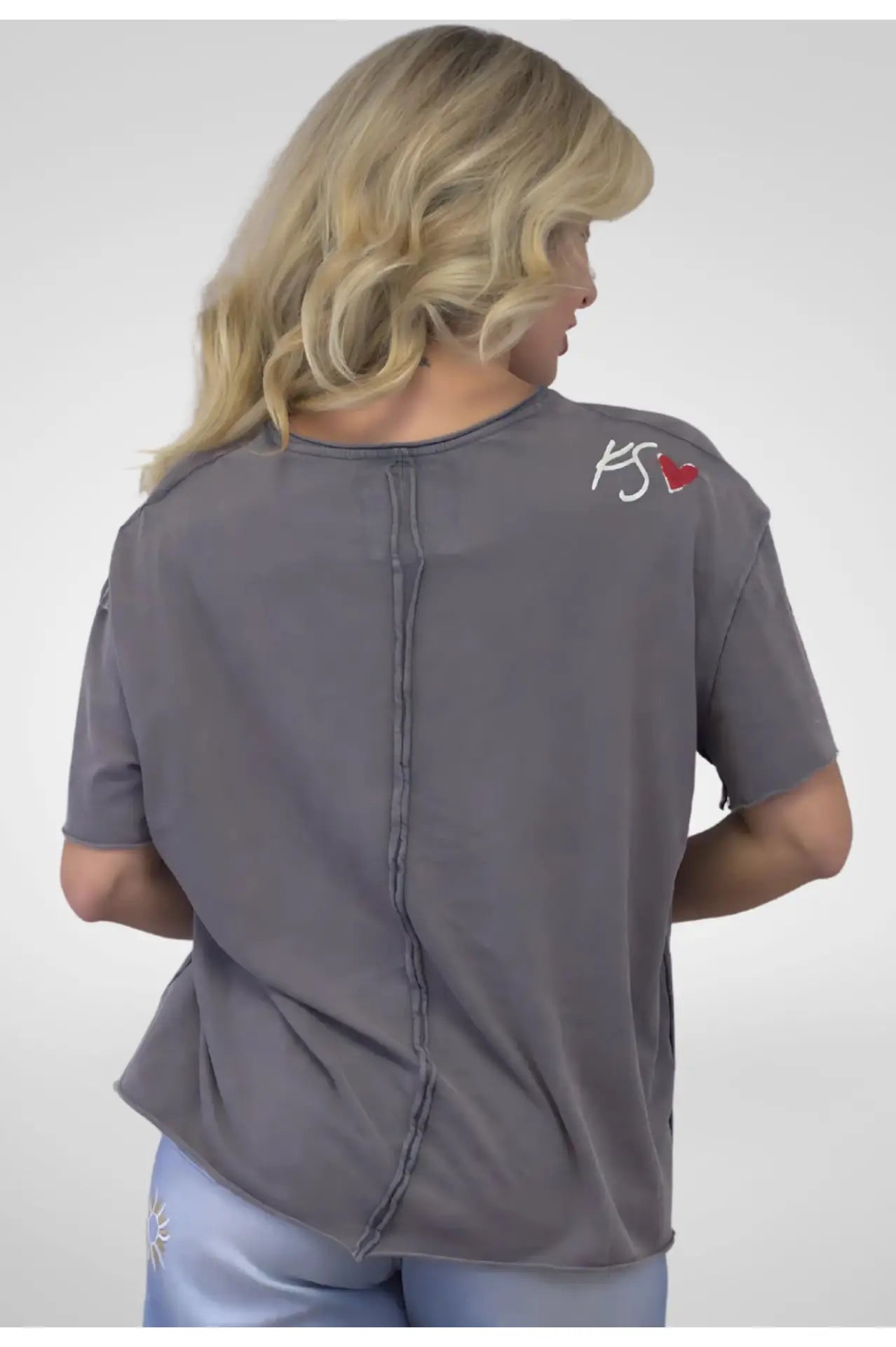 Person wearing a gray shirt with a logo on the back against a white background