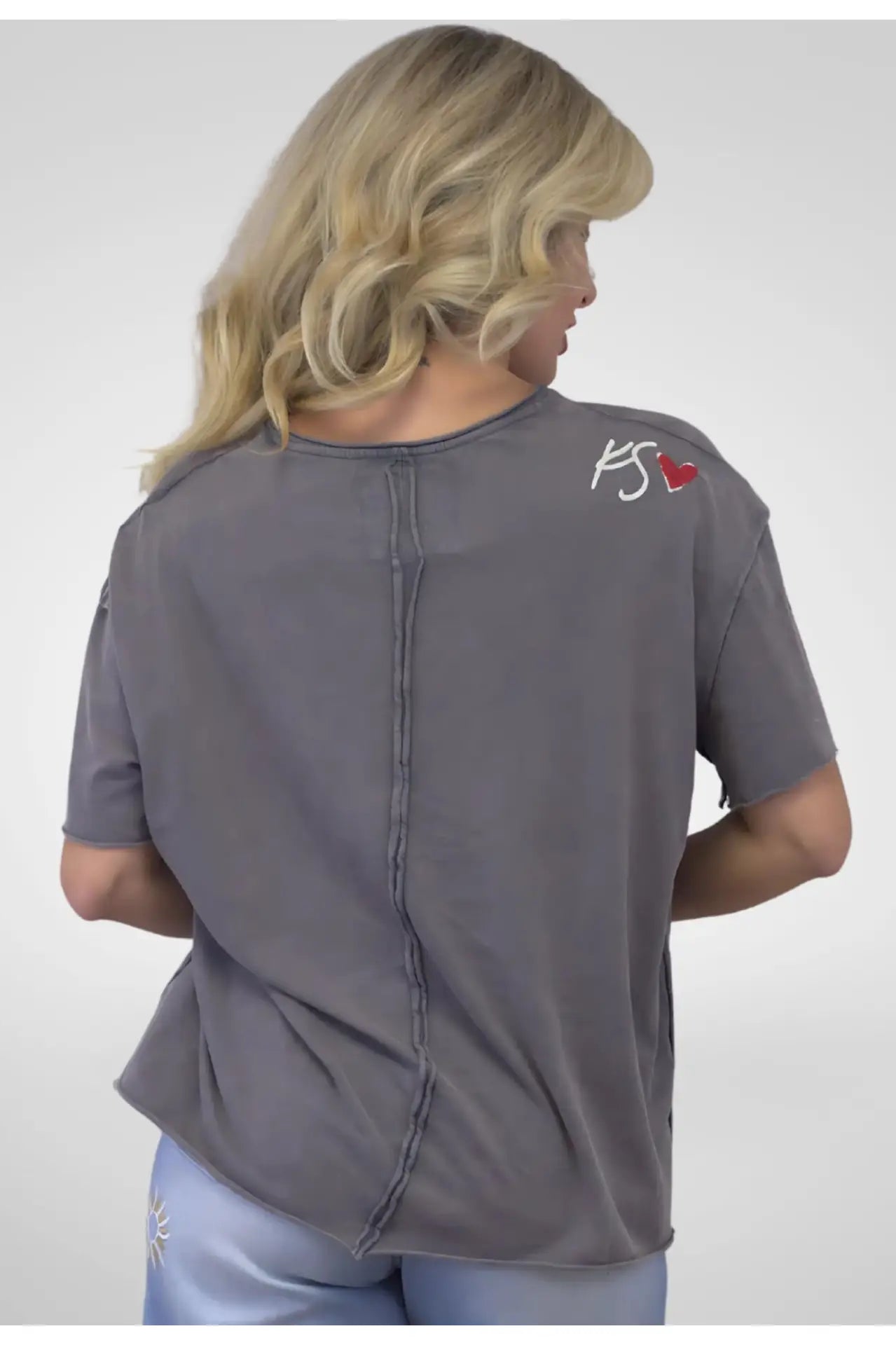 Person wearing a gray shirt with a logo on the back against a white background
