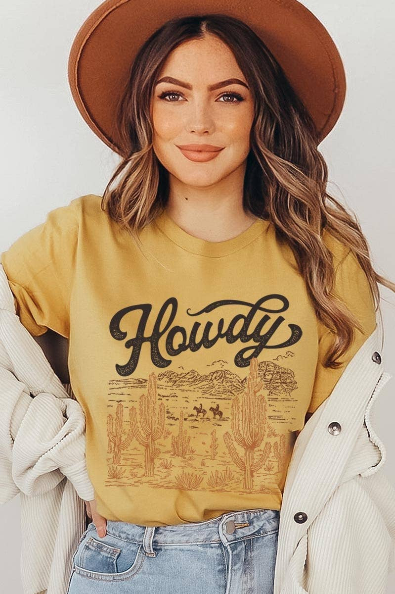 Mustard yellow Bella + Canvas graphic tee featuring a vintage "Howdy" western design with a desert landscape, cacti, and relaxed unisex fit.