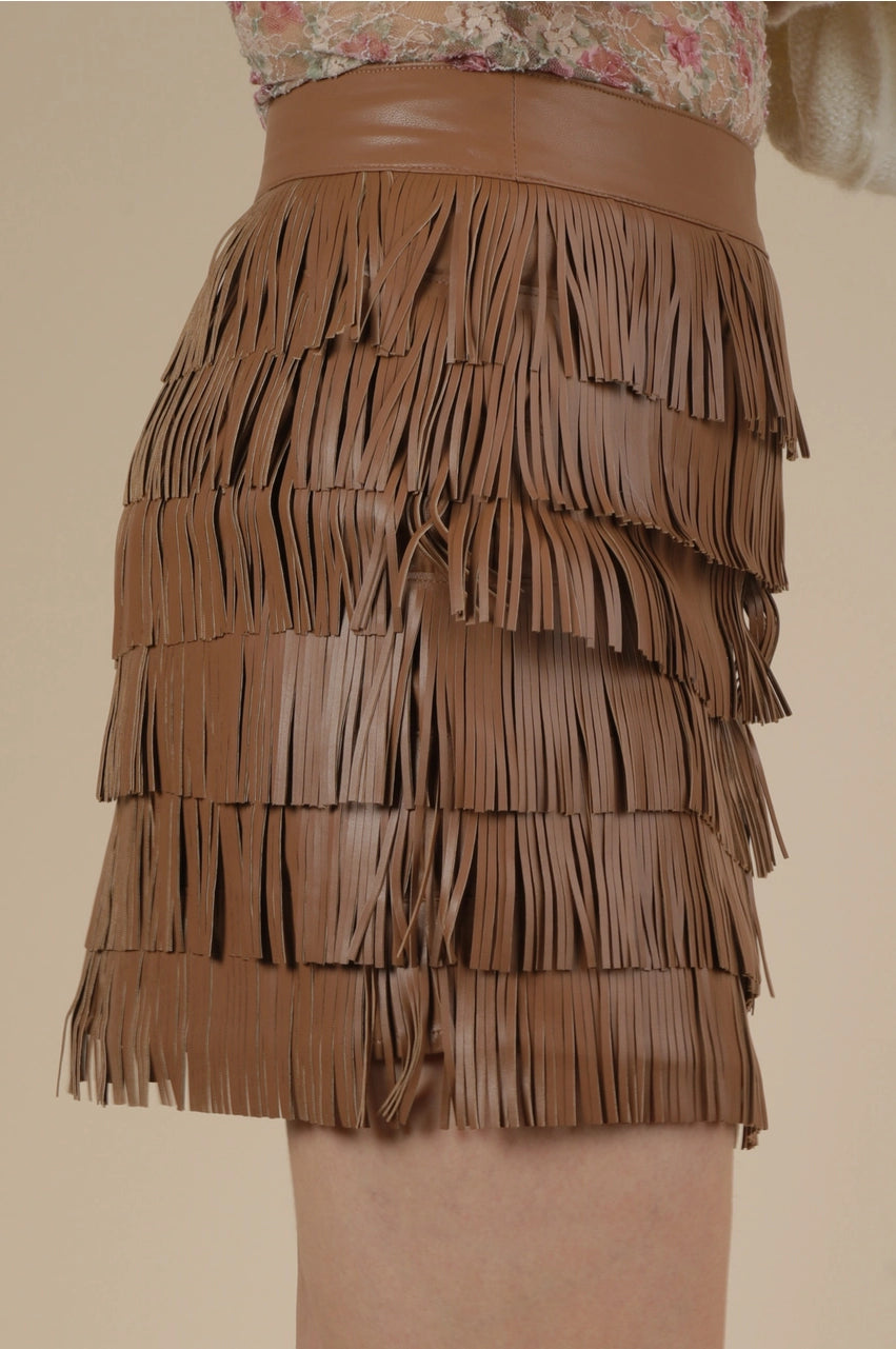 Side view of brown fringe mini skirt in vegan leather with multi-tier tassels