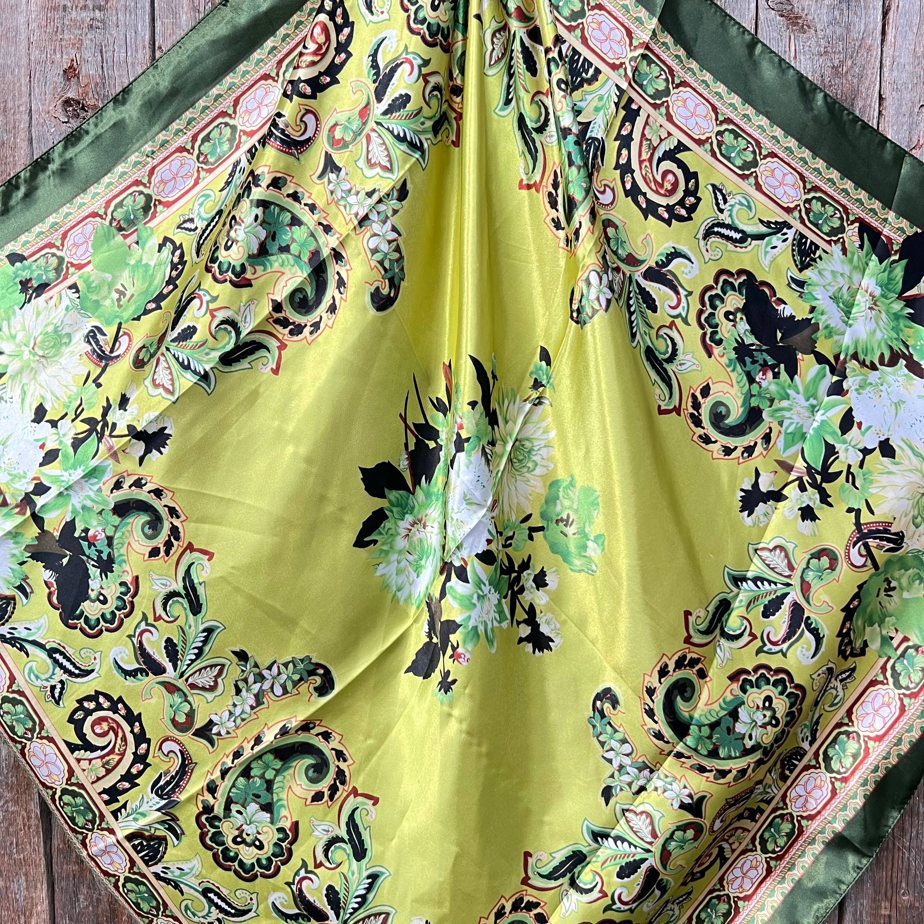 Yellow fabric with intricate green and black patterns on a wooden surface