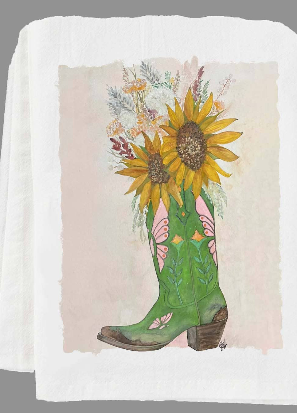 Green cowboy boot with sunflowers and floral design on a folded white tea towel.