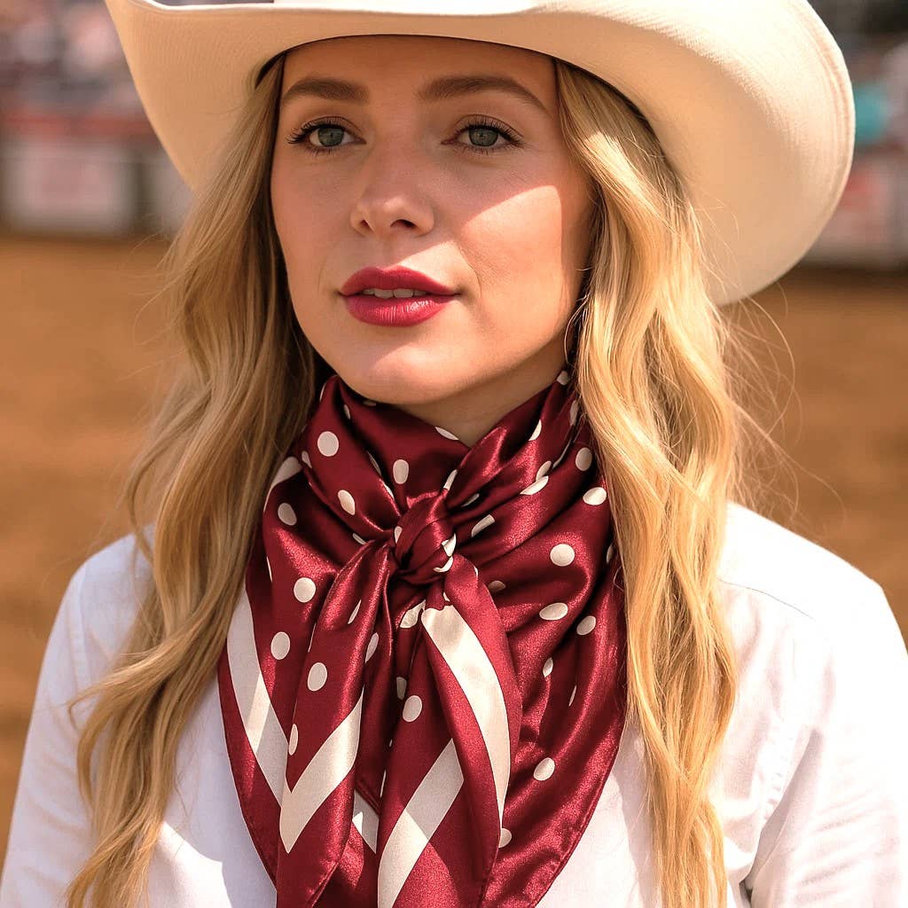 Woman wearing a beige cowboy hat and red polka dot scarf in an outdoor setting