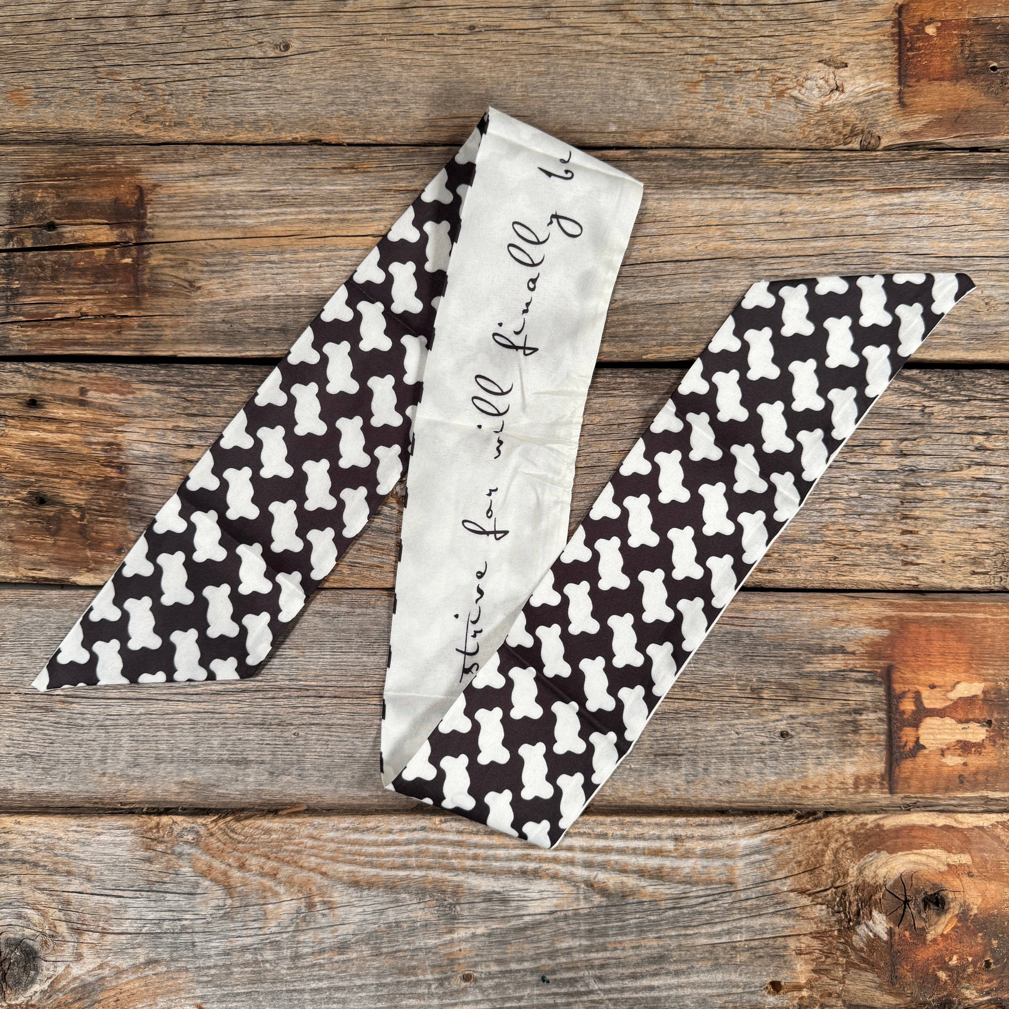 Black and white patterned thin scarf on a wooden surface.