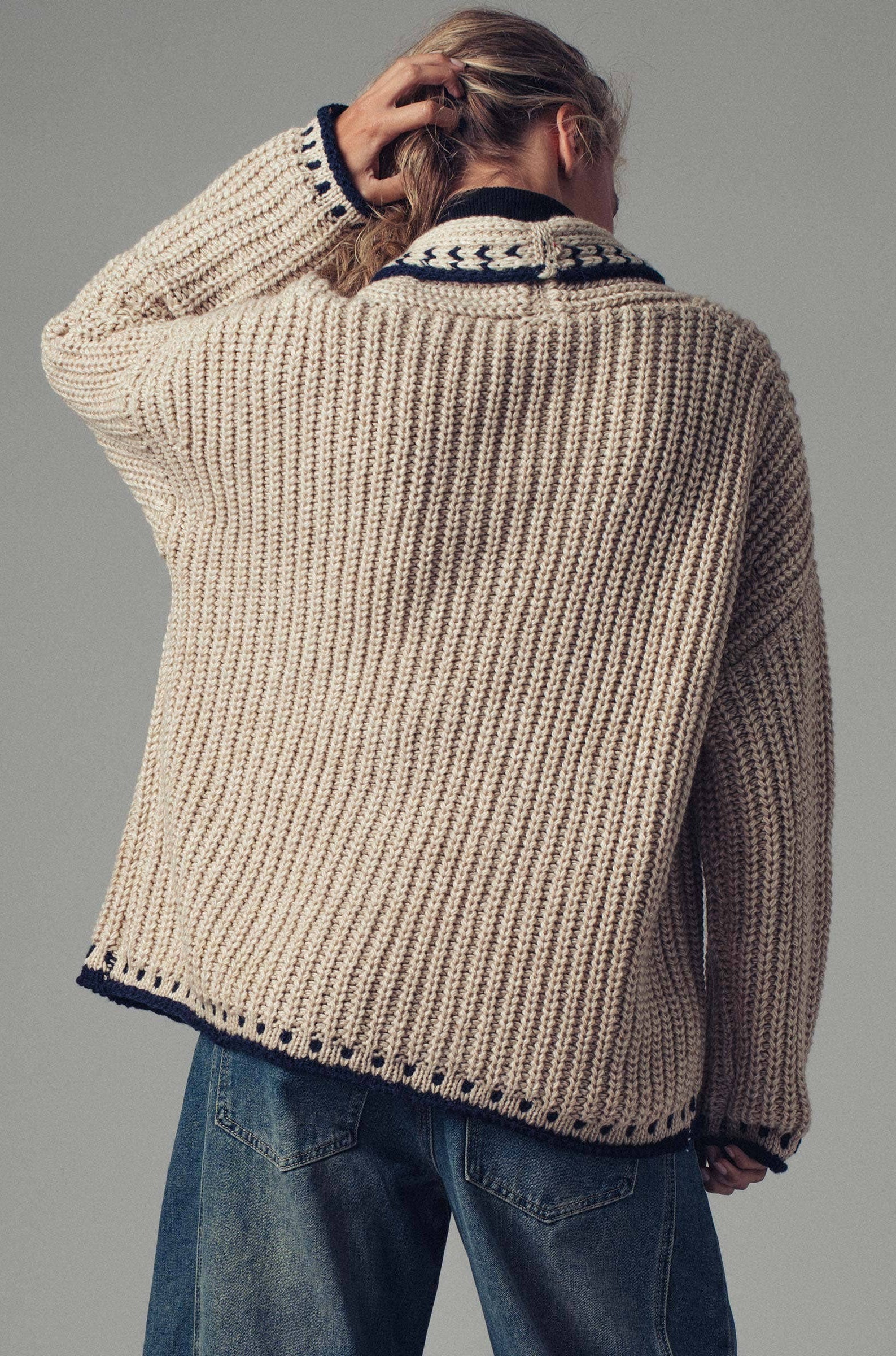 Back of Person wearing a chunky knit sweater with a gray background