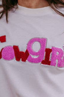 White sweatshirt with 'Cowgirl' text in red and pink on a blurred background