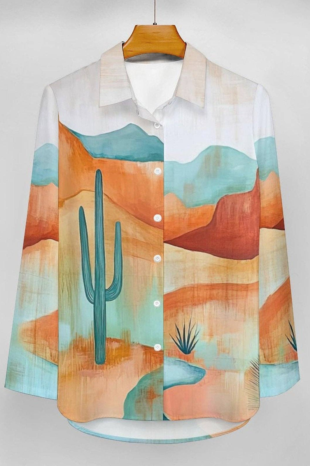 Colorful shirt with desert landscape design on a hanger against a white background