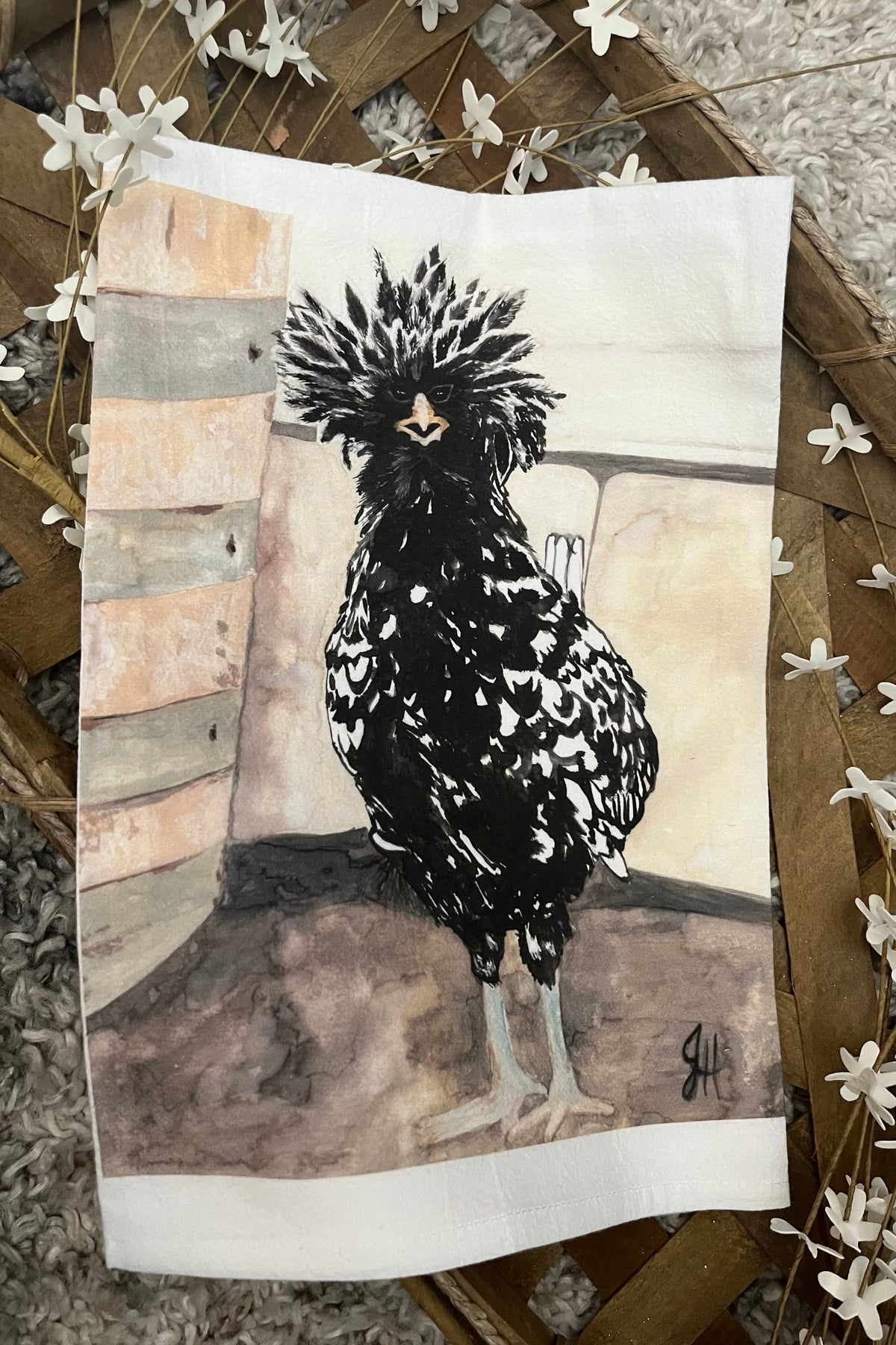 Artistic depiction of a rooster on a textured surface of a white tea towel.