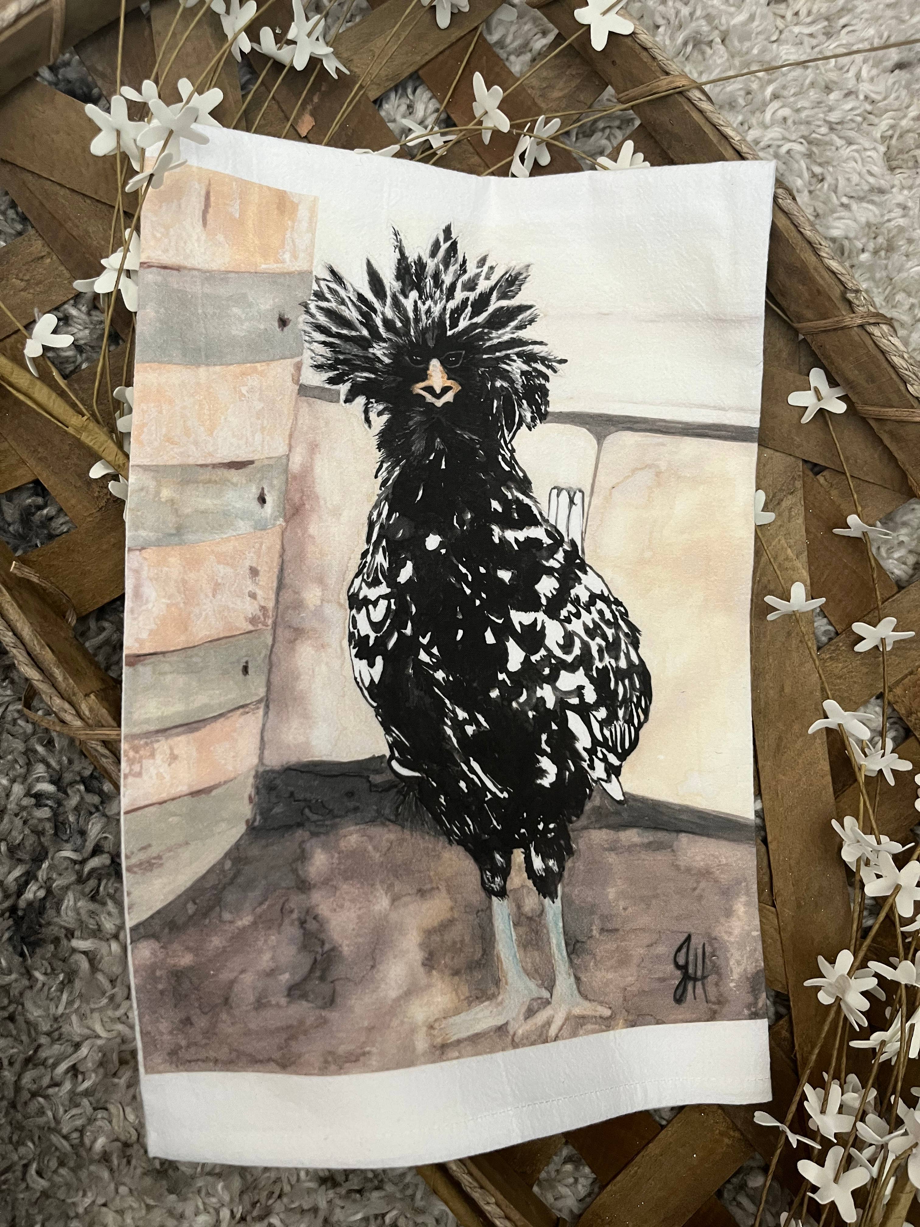 Artistic depiction of a rooster on a textured surface of a white tea towel.