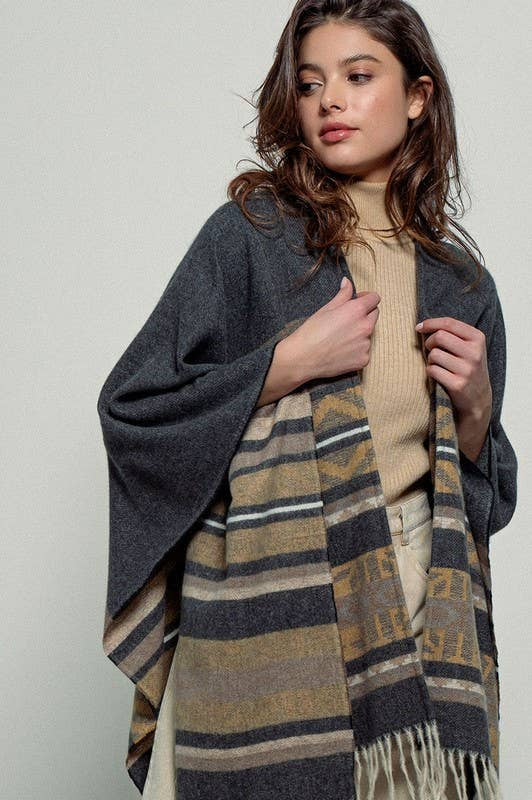Dark gray poncho with brown and beige striped pattern and fringes on a white background