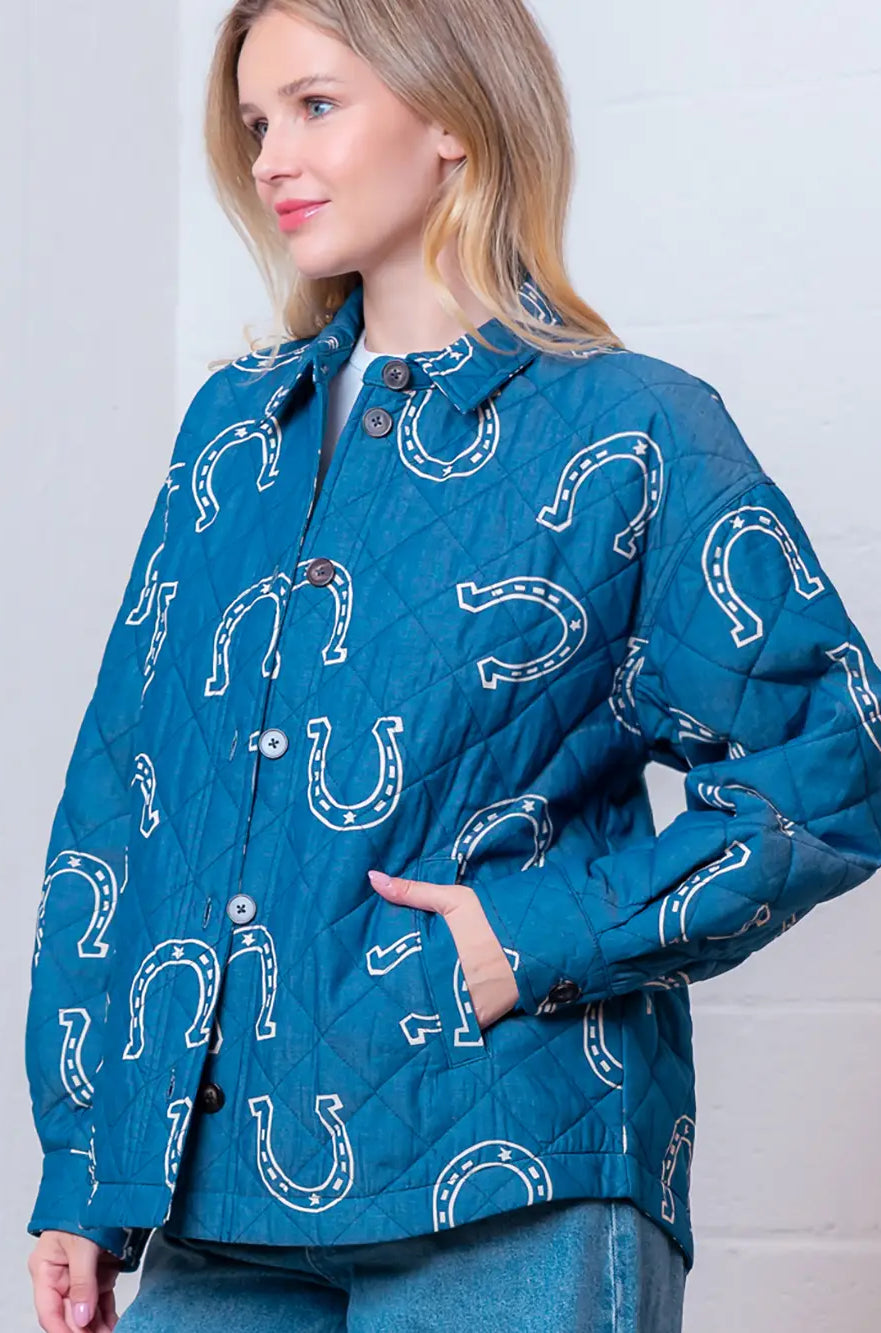Front view of denim-blue quilted jacket with white horseshoe print and button front on model.