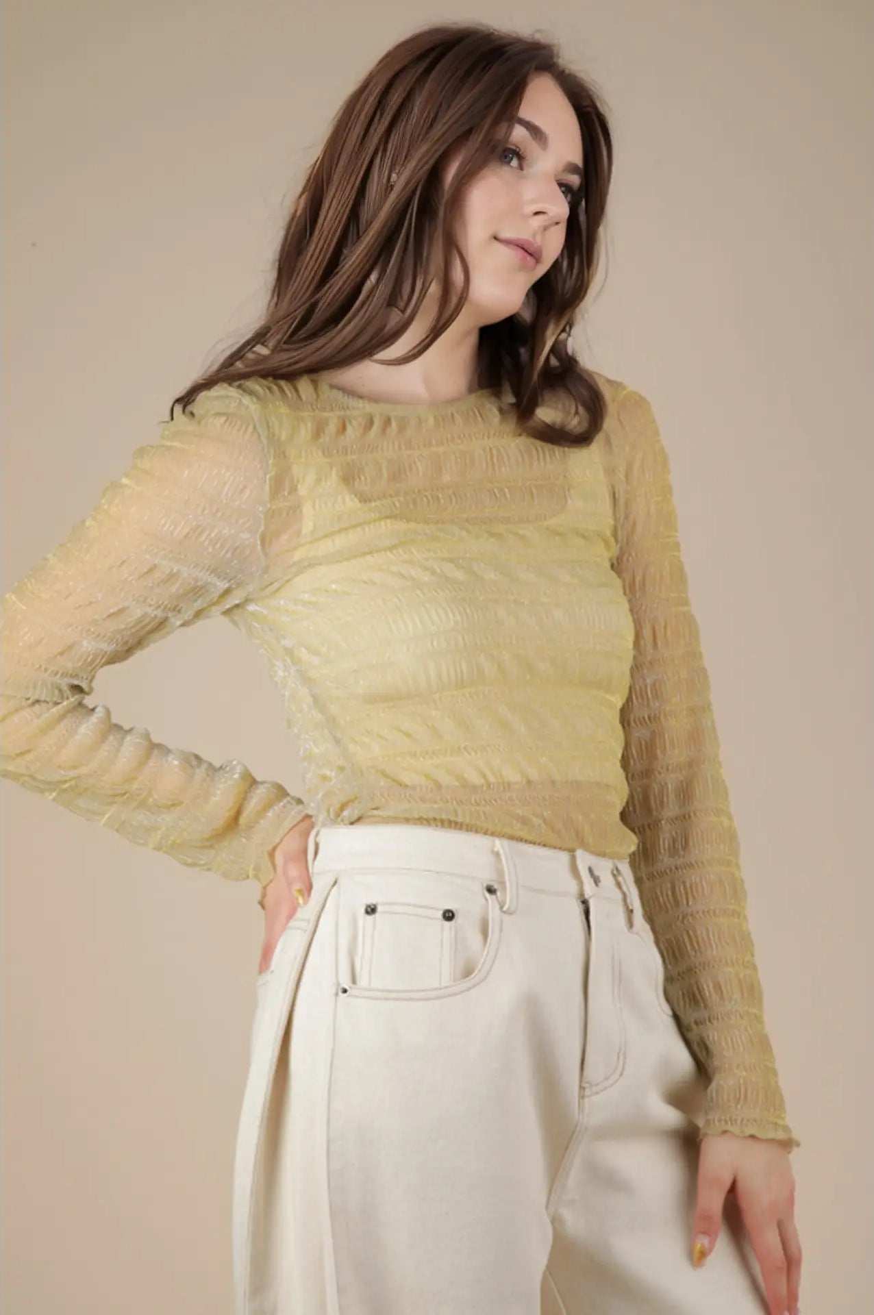 Front view: Model wearing champagne sheer lurex long-sleeve fitted top with crew/mock neck; subtle sparkle visible.
