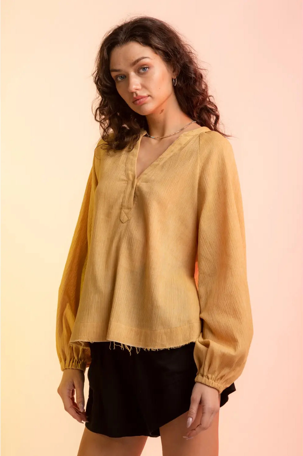Model wearing yellow gauze V-neck blouse with raglan bubble sleeves and raw hem,