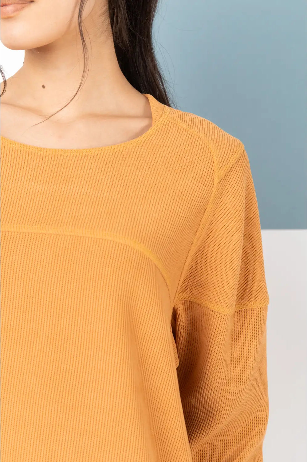 Yellow ribbed sweater worn by a person against a light blue and white background