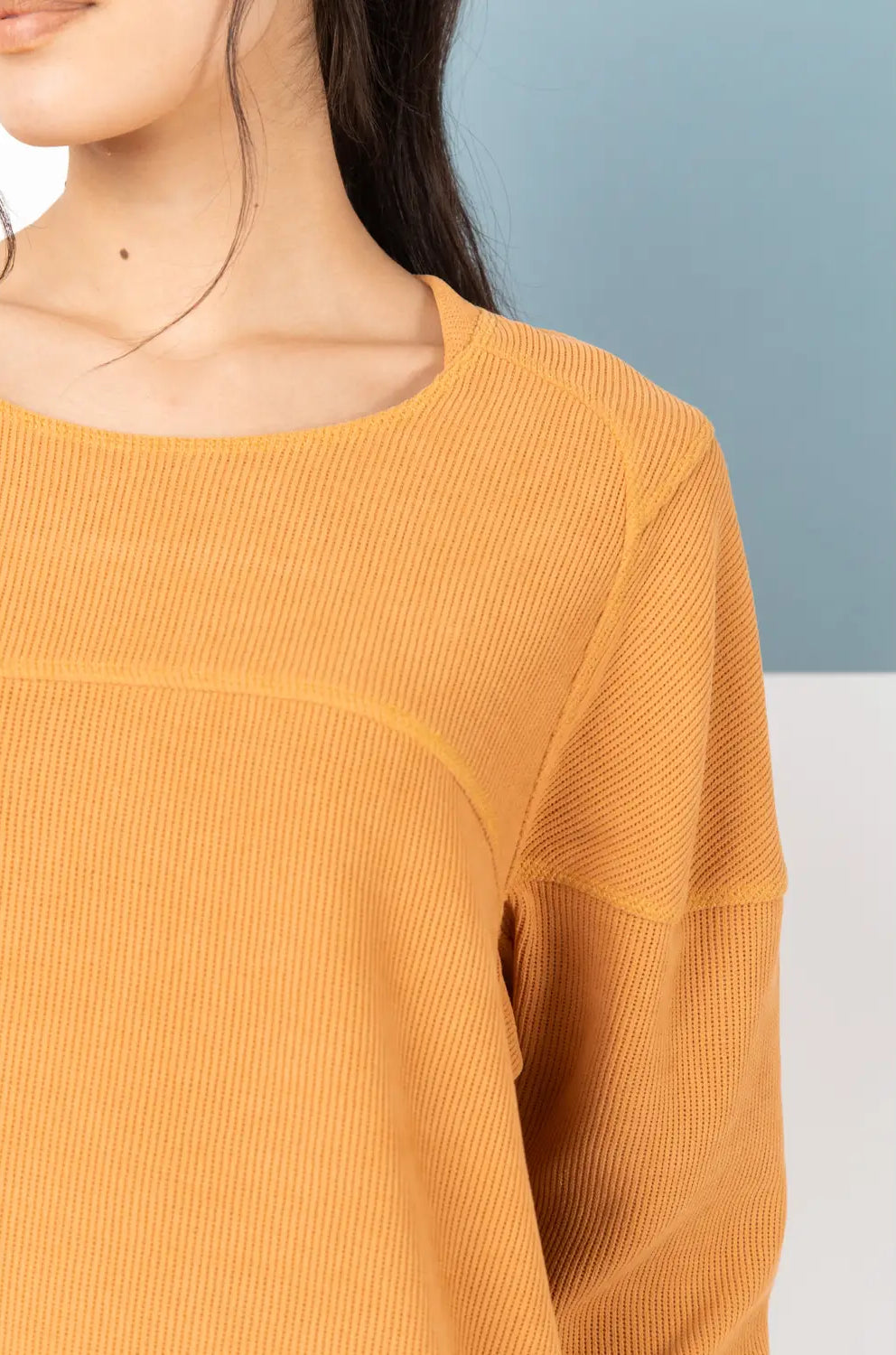 Yellow ribbed sweater worn by a person against a light blue and white background