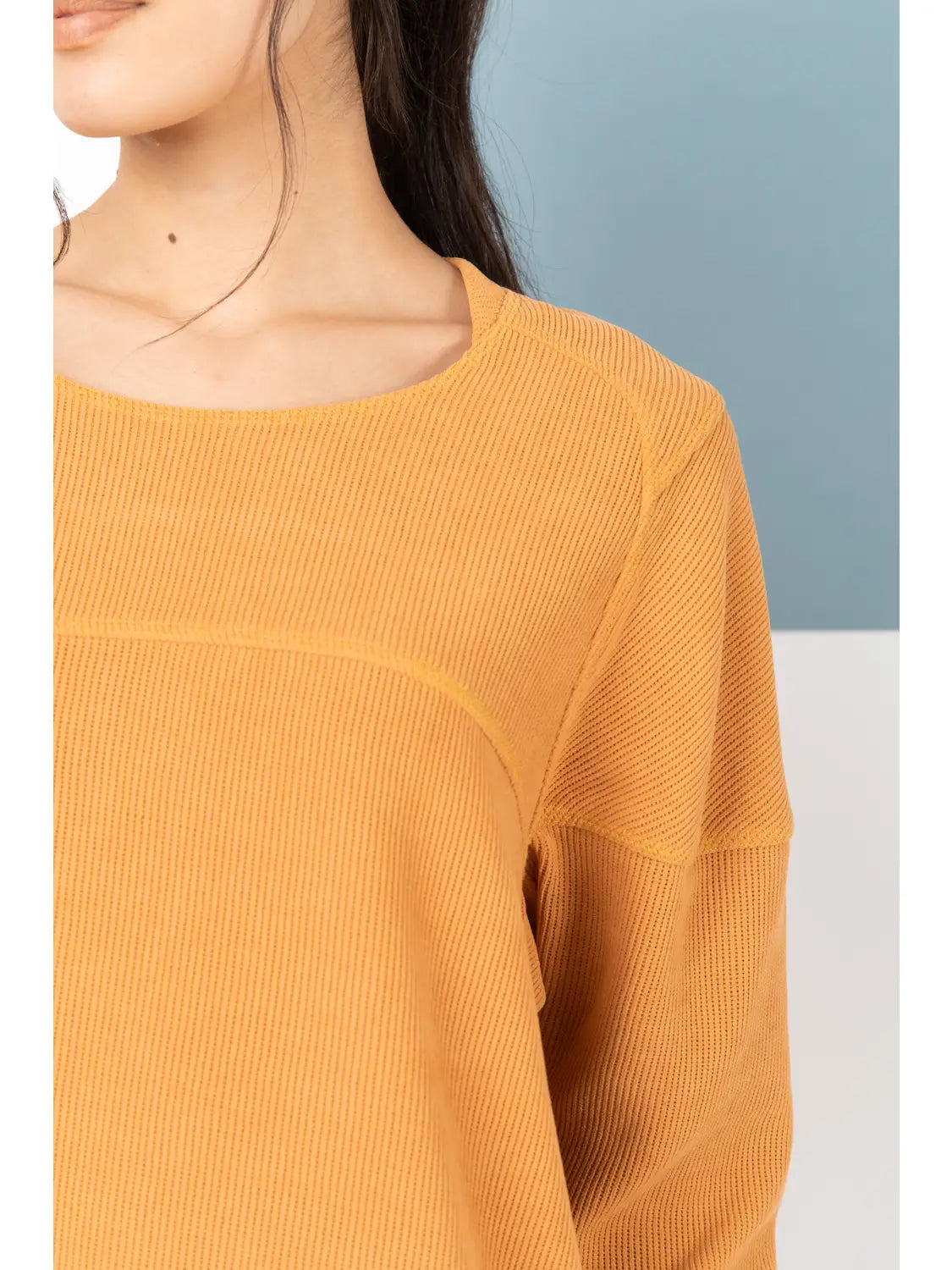 Yellow ribbed sweater worn by a person against a light blue and white background
