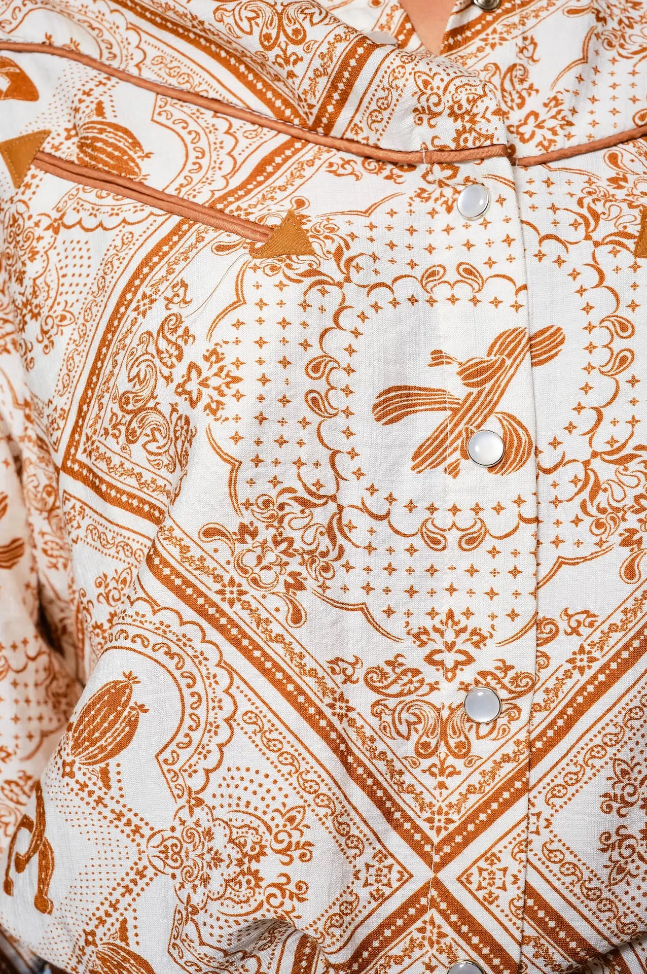 Woman wearing a western patterned blouse western color details snap shirt and jeans