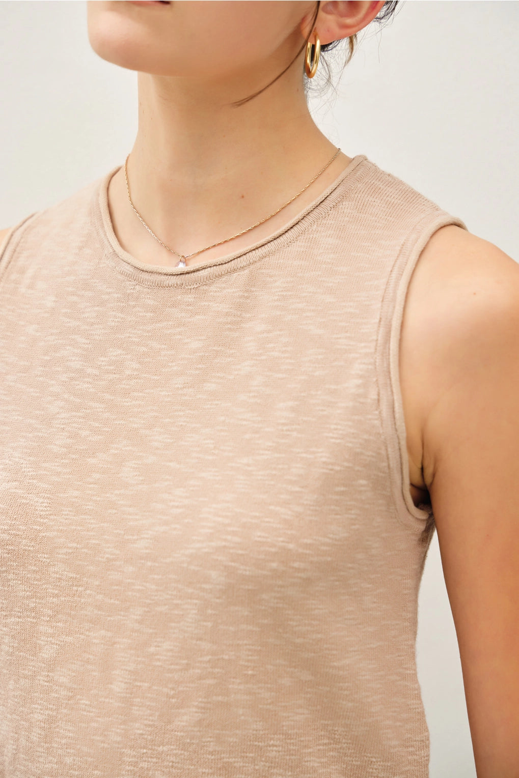 Beige sleeveless top worn by a person on a light gray background