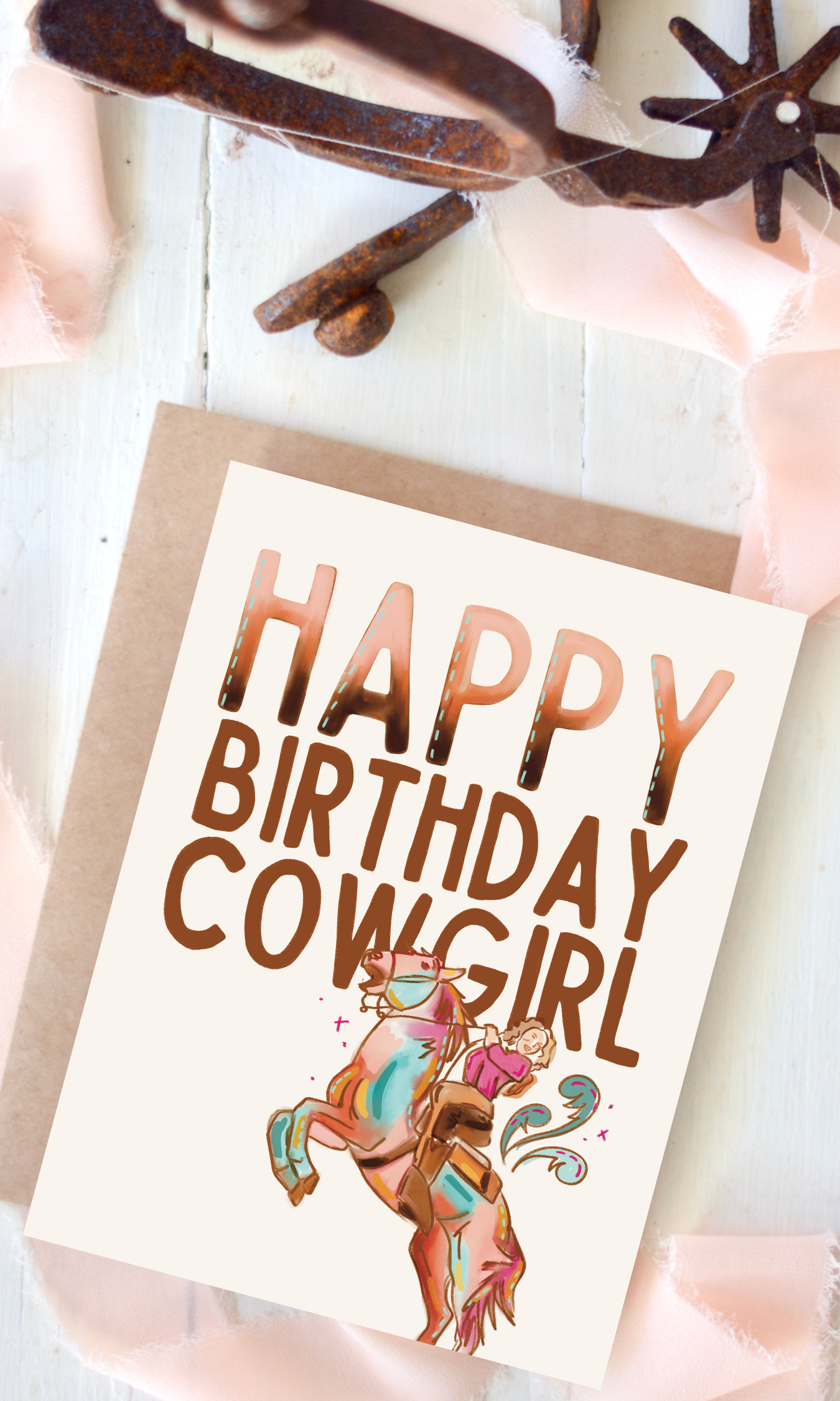A greeting card with the text 'HAPPY BIRTHDAY COWGIRL' displayed in a bold, copper-colored font. The card features an illustration of a cowgirl riding a turquoise mustang.
