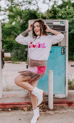 Woman posing in front of a vintage gas pump wearing a 'Girl' sweatshirt.