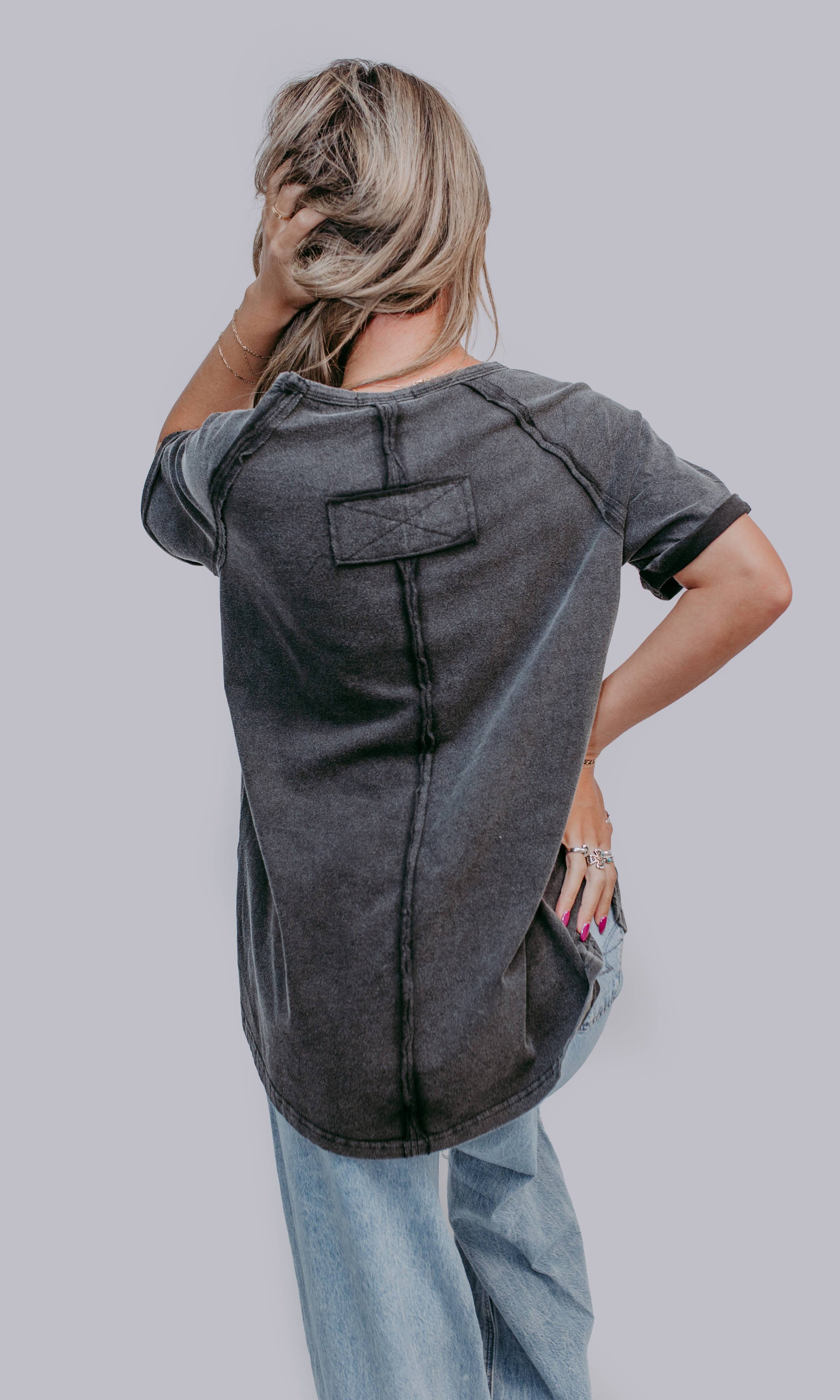 Person wearing a gray t-shirt with a unique design on a plain background