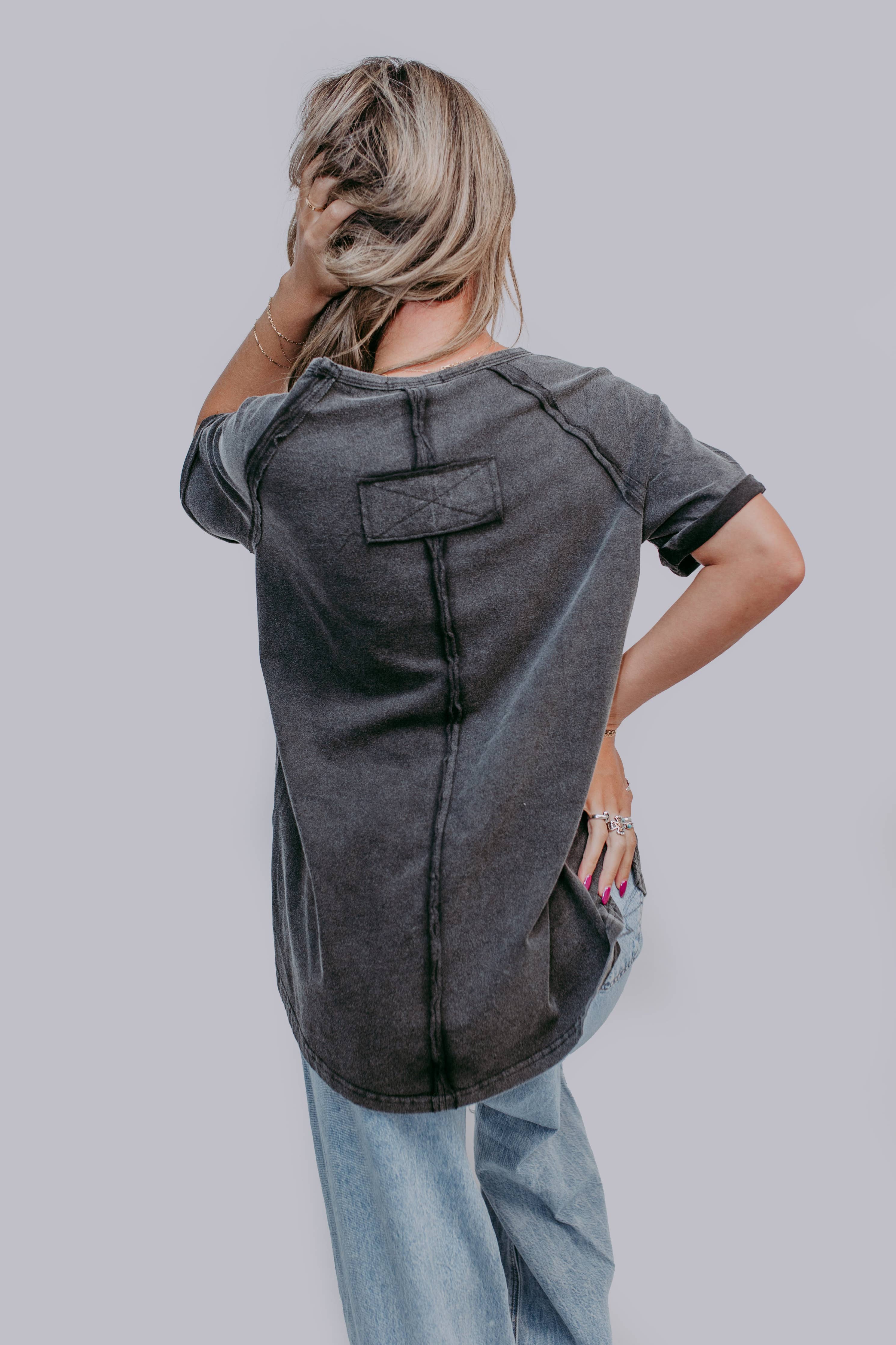 Person wearing a gray t-shirt with a unique design on a plain background