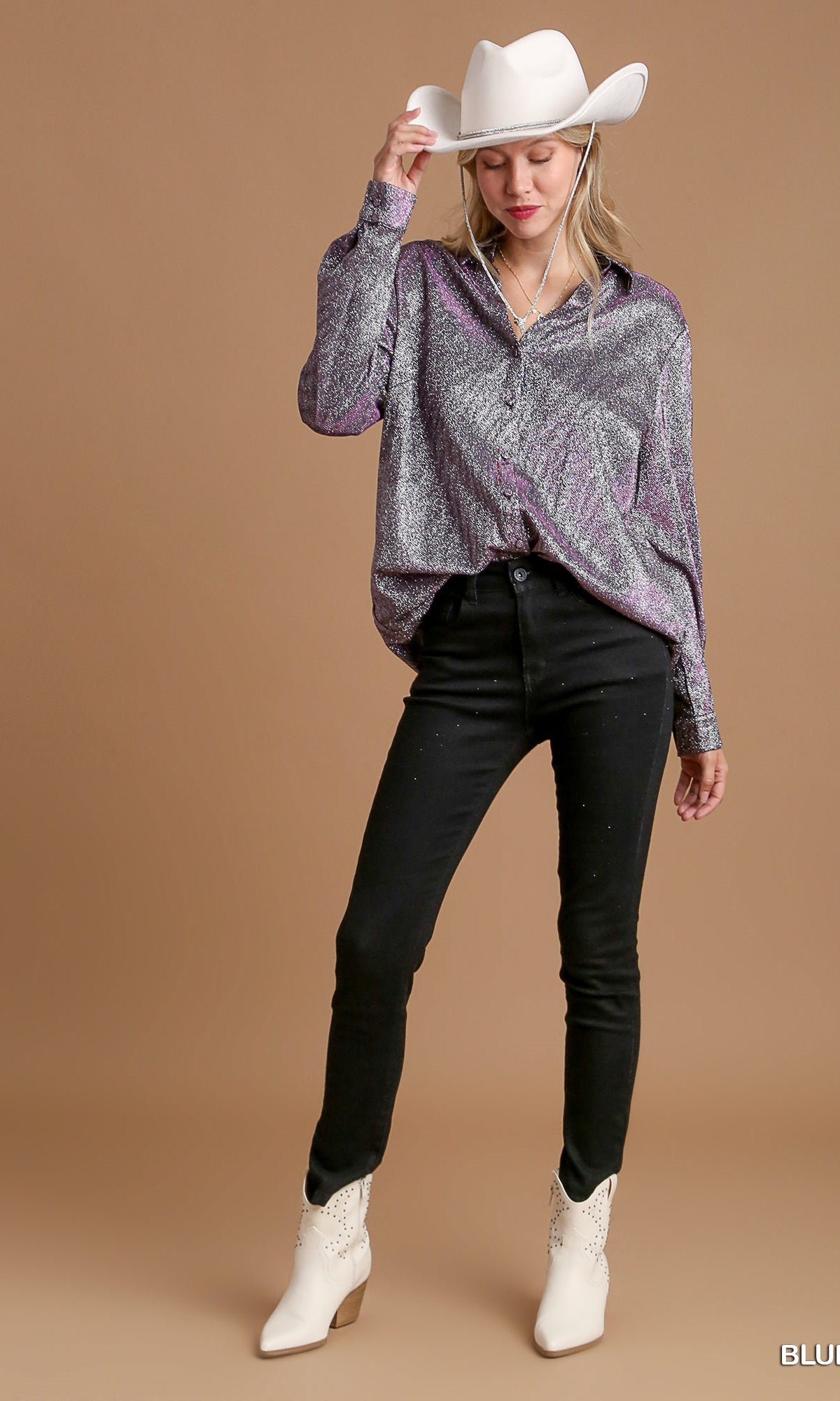 Woman wearing a patterned top, black pants, and white boots against a brown background