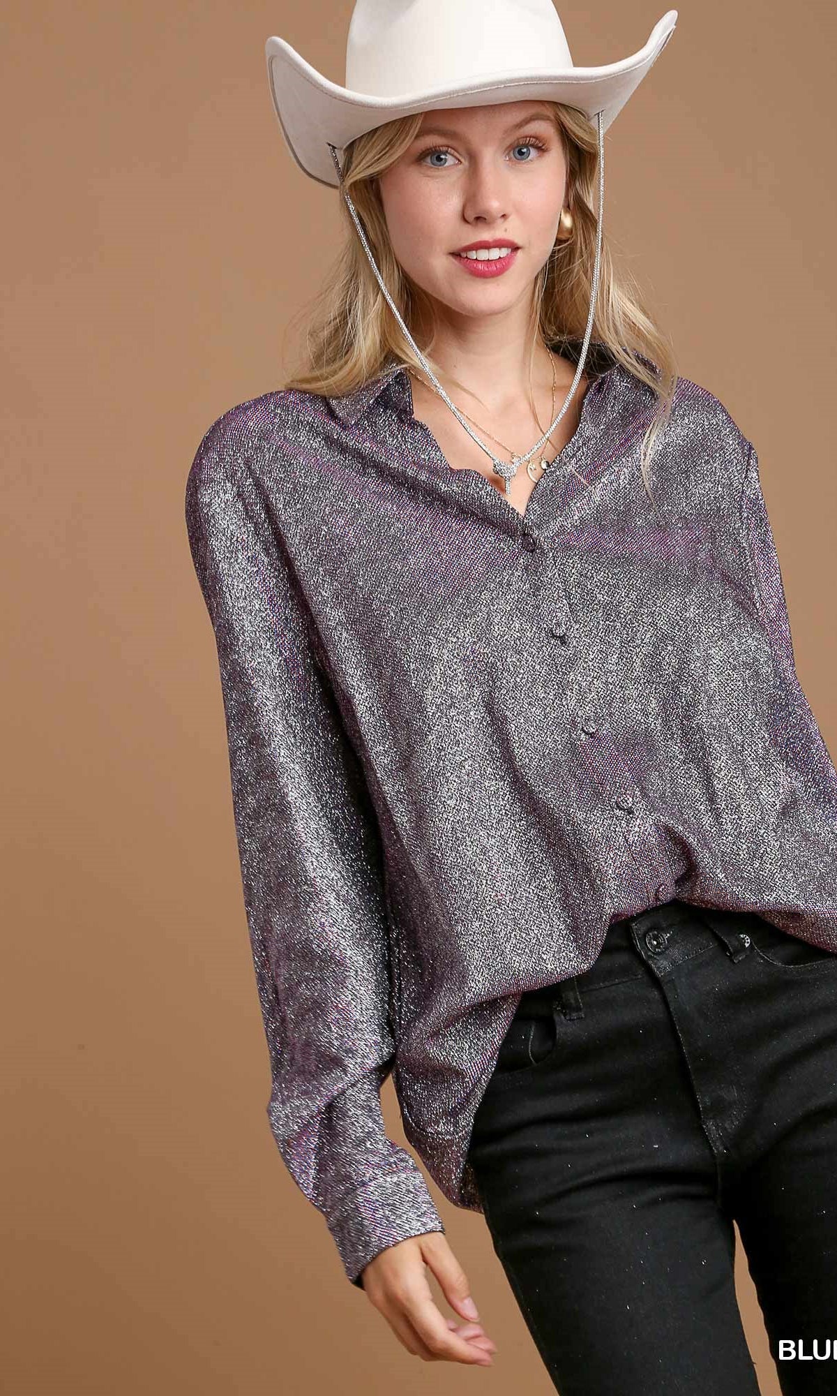 Woman wearing a sparkly silver shirt and white cowboy hat on a brown background