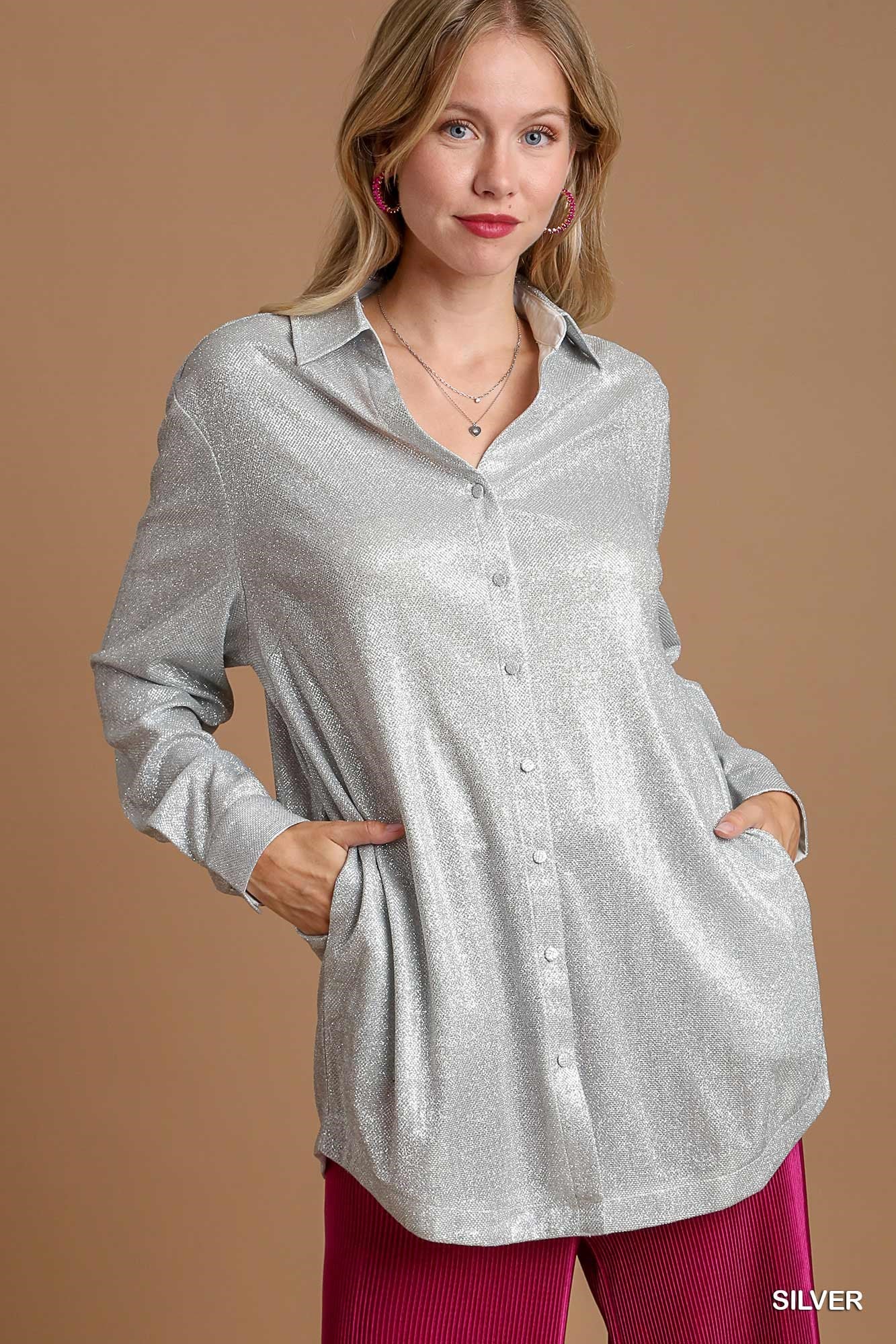 Woman wearing a silver button-up shirt against a beige background